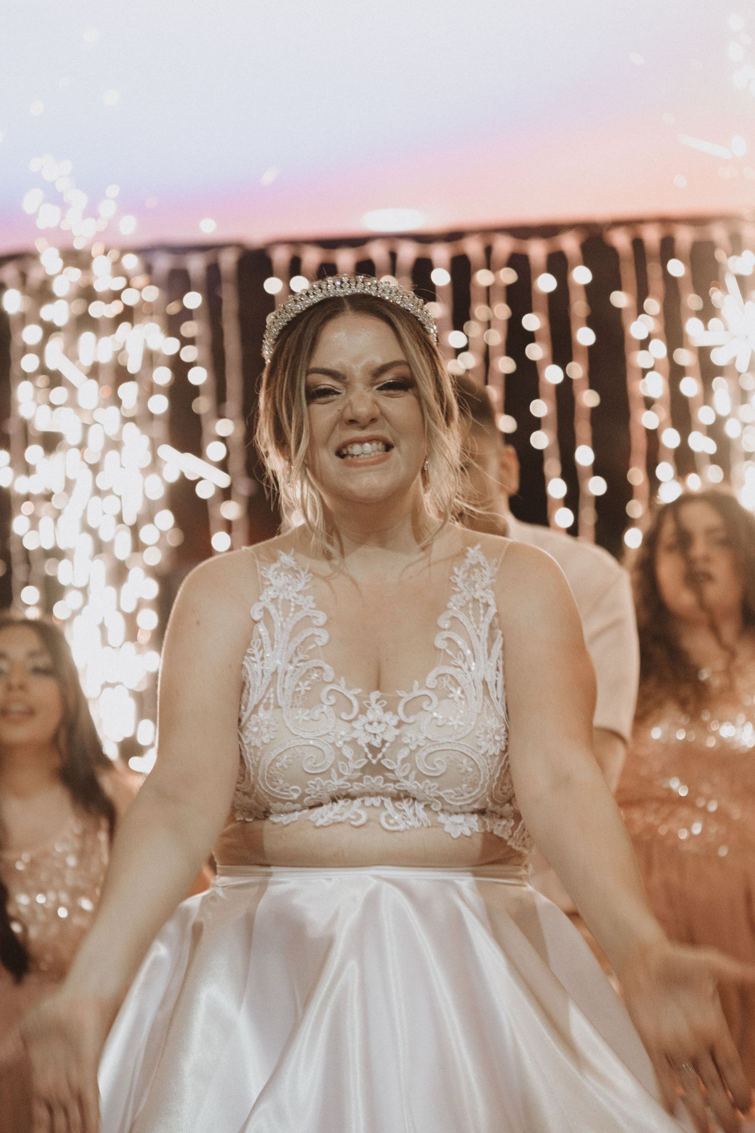 Close-up of bridal attire with lace details against a backdrop of string lights.