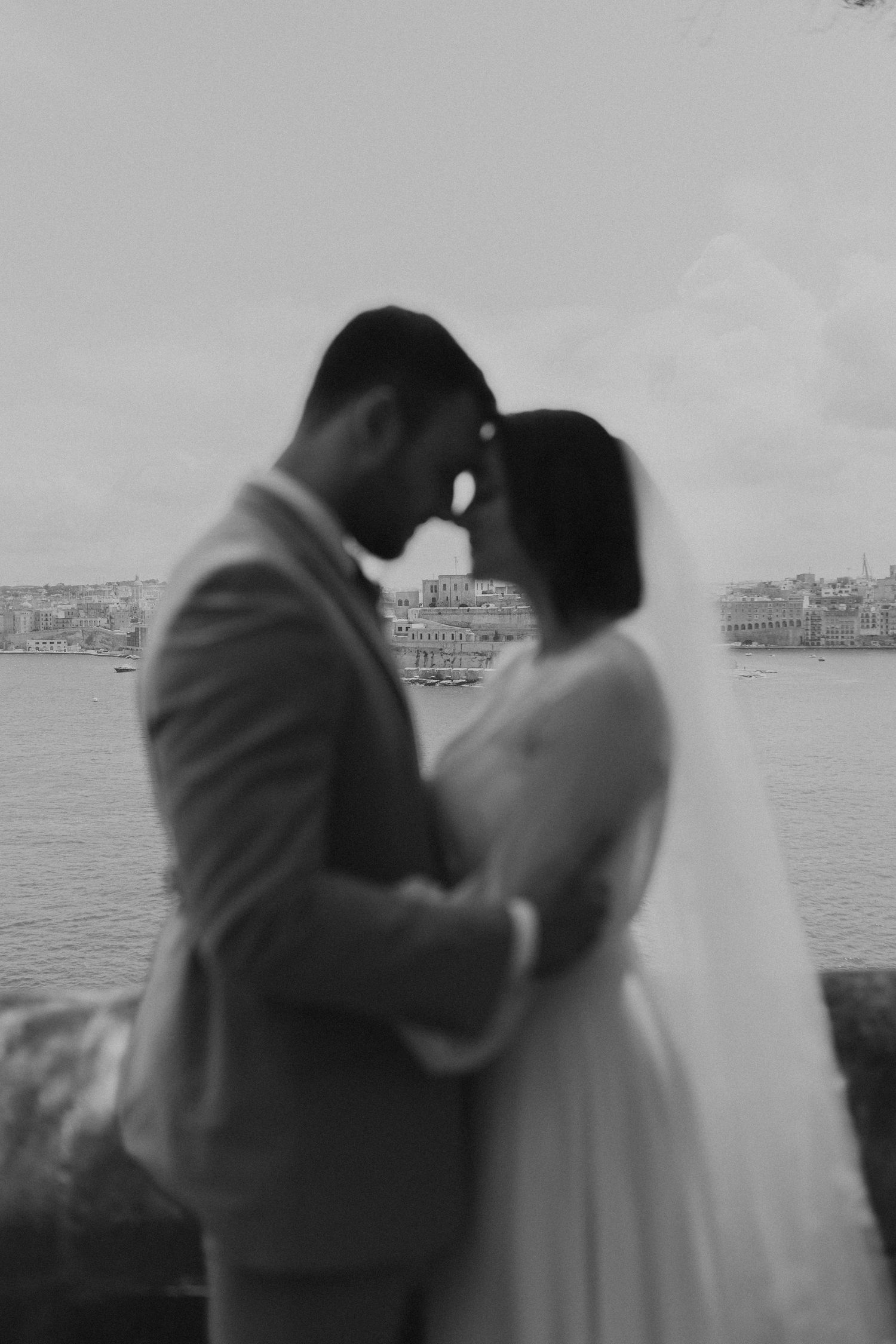 Romantic black and white portrait of newlyweds by the water.
