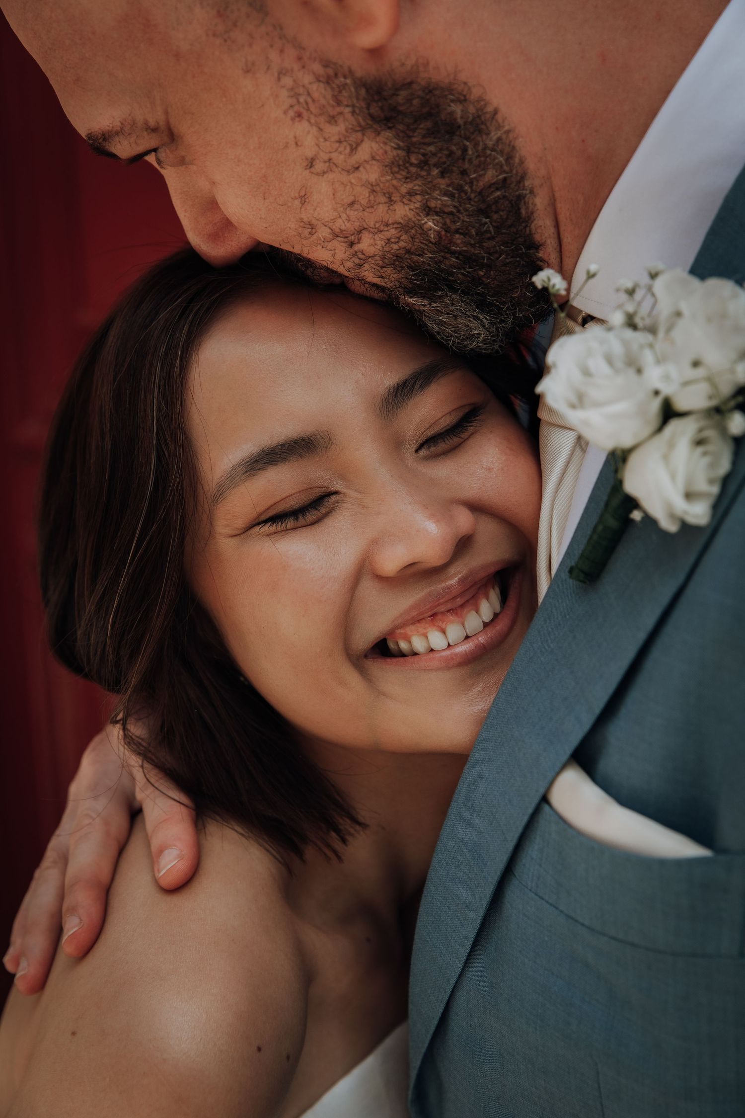 An intimate close-up wedding photo showing joyful expressions and a white floral boutonniere.