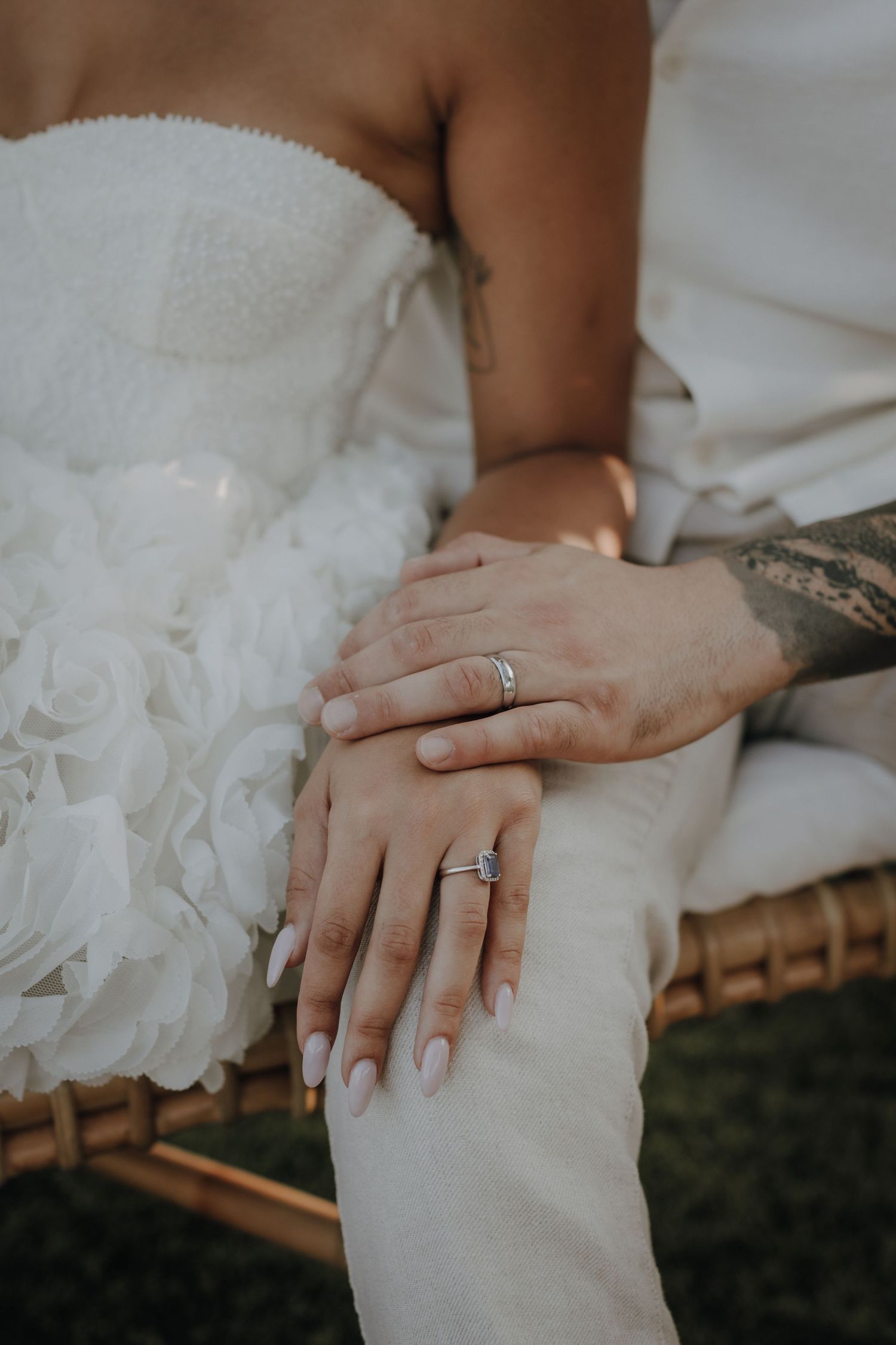 Close-up shots of wedding rings and hands on white wedding dress fabric.