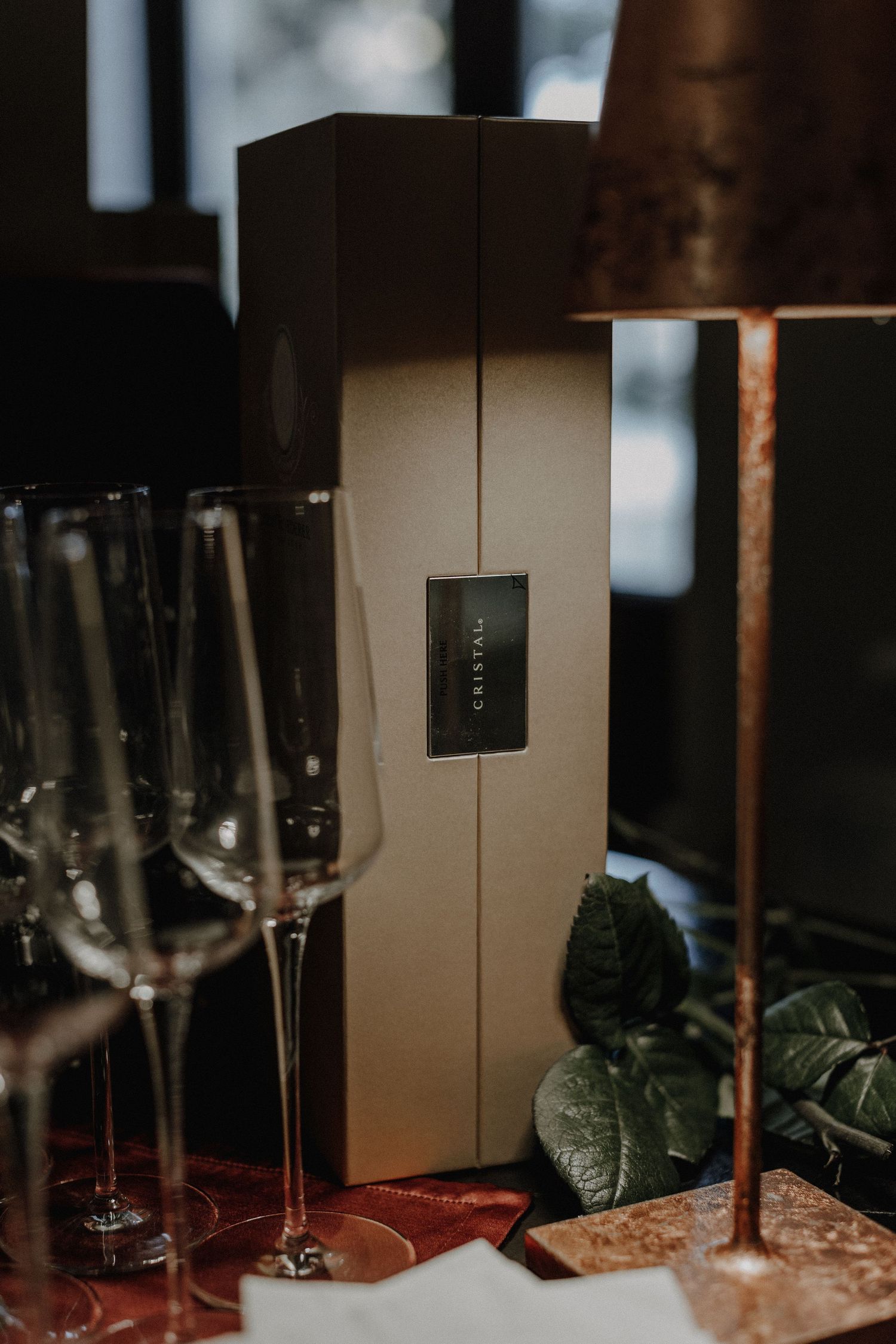 Elegant wine bottle packaging with champagne flutes and table lamp in soft focus.
