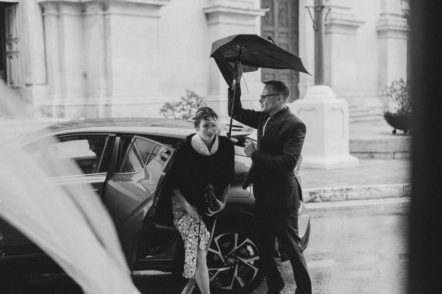Vintage black and white photo of rainy day arrival at historic building.