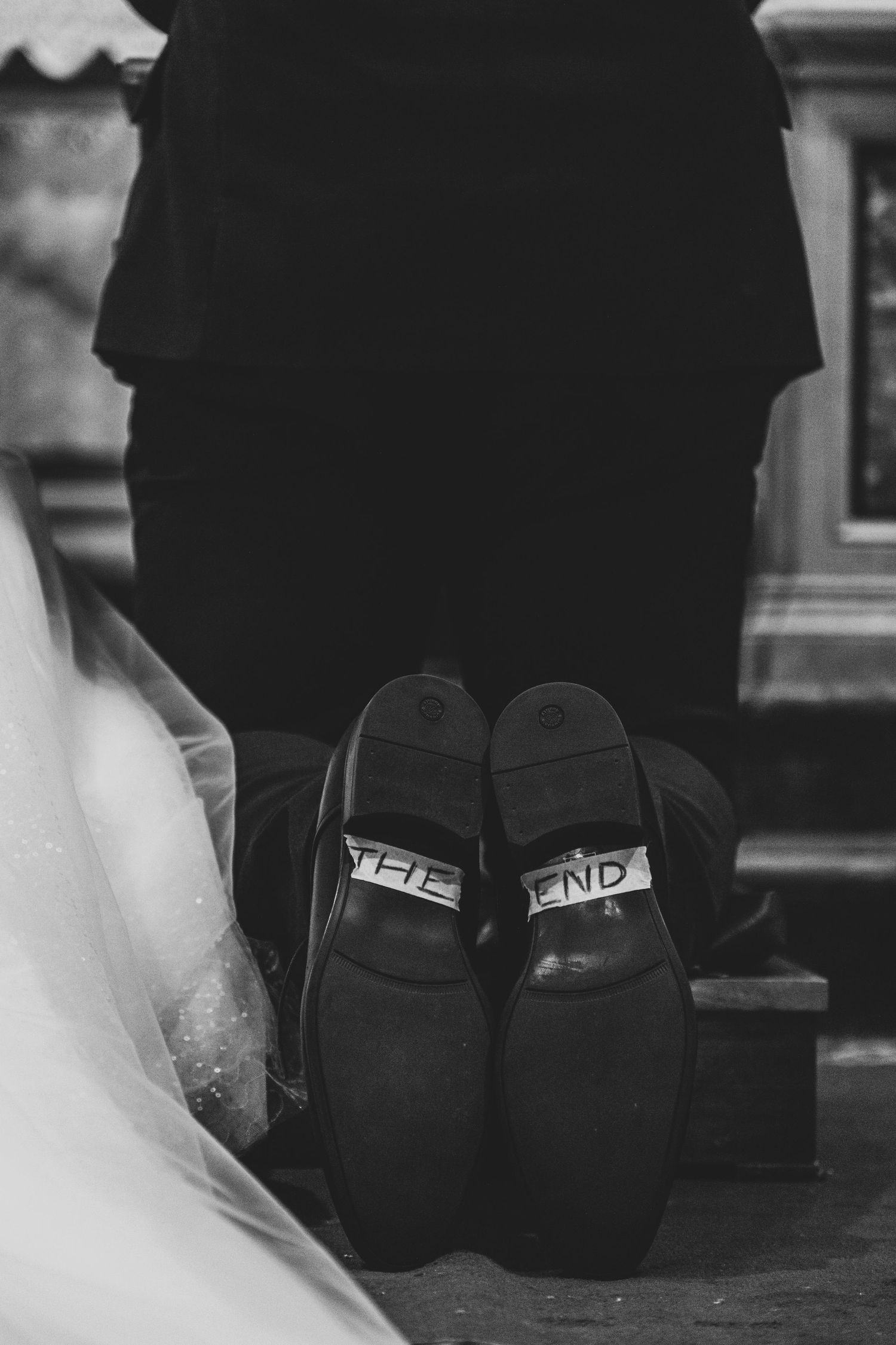 Black and white detail shot of wedding shoes with 'The End' written on the soles.