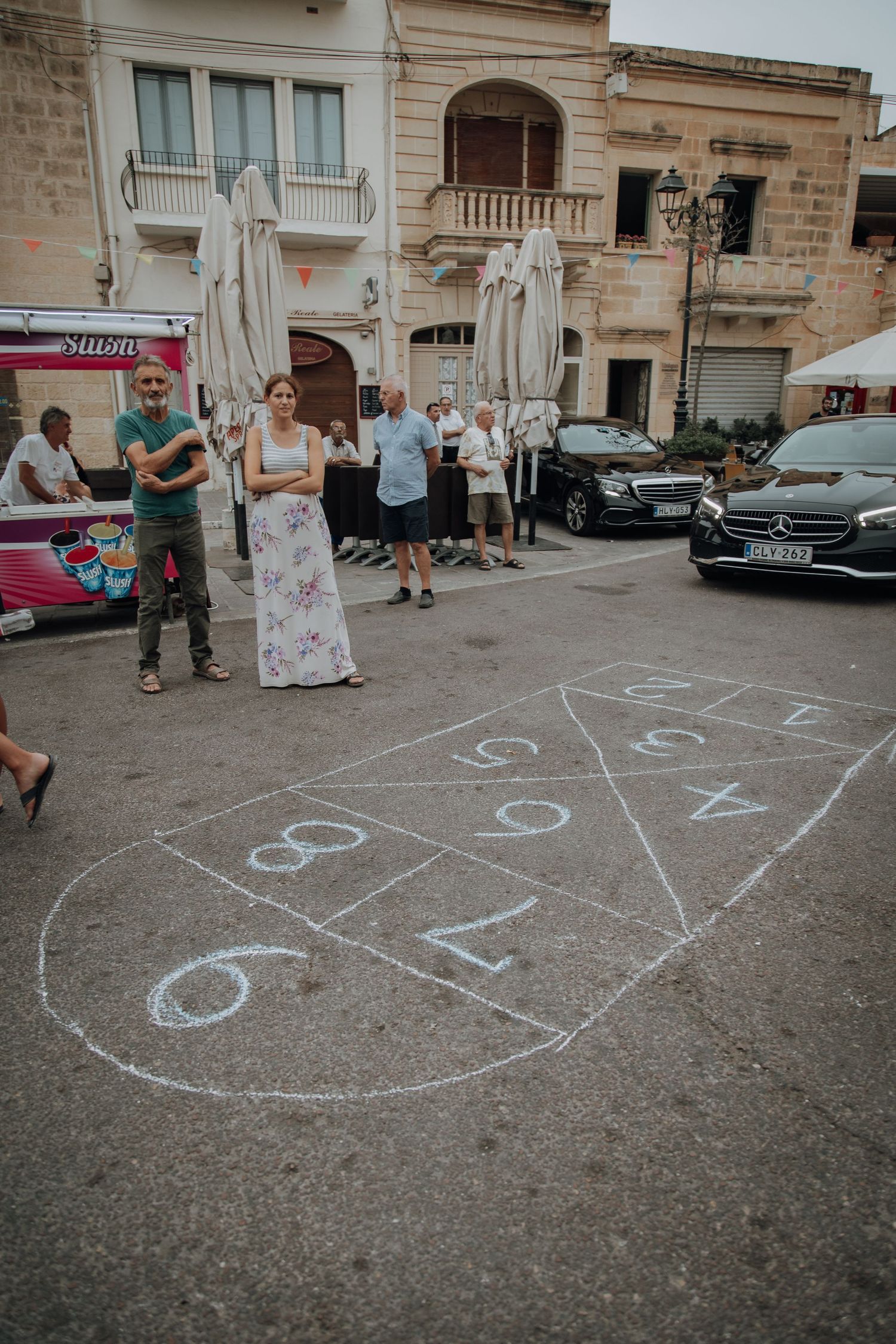 Hopscotch game drawn in chalk on street pavement during casual wedding celebration.