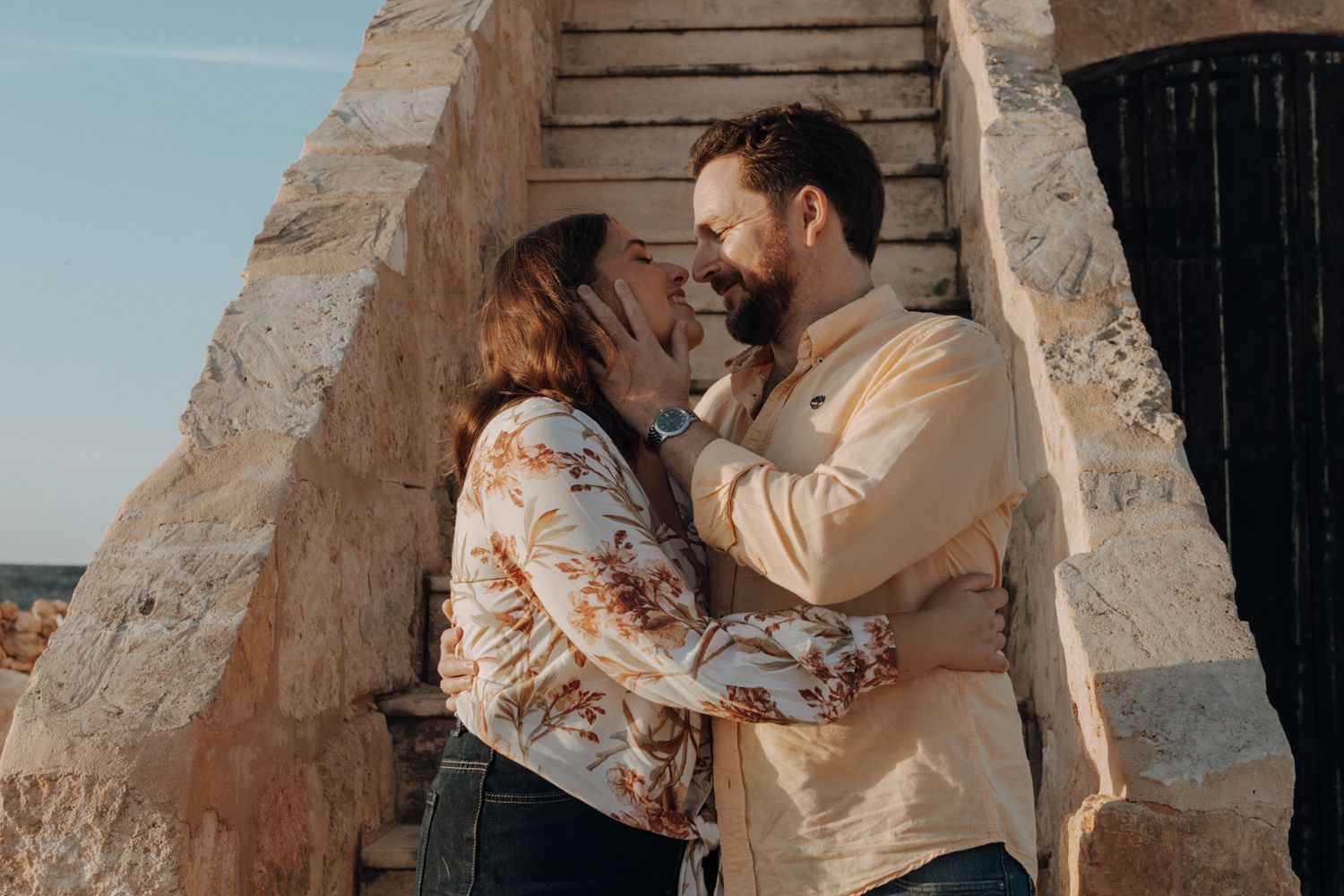 A romantic couple embraces and shares intimate moments in a desert landscape at sunset.