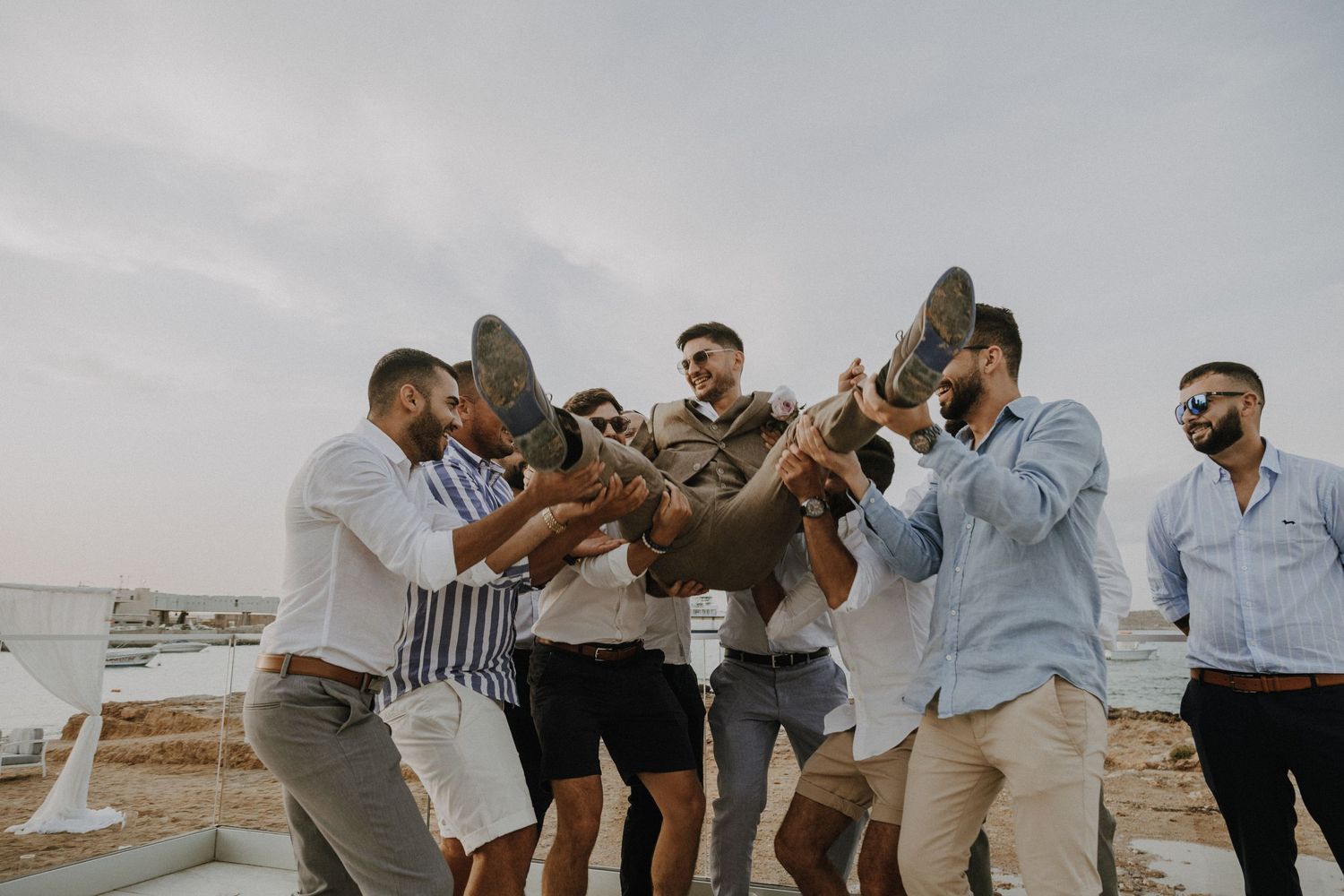 Friends in casual attire jumping and celebrating together against an overcast sky.