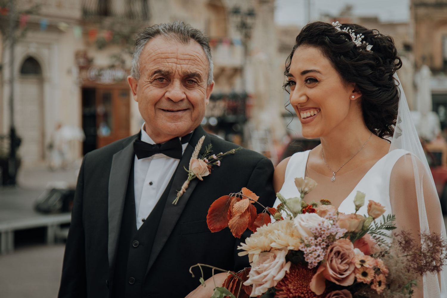Joyful moment captured between bride and companion outside historic stone building.