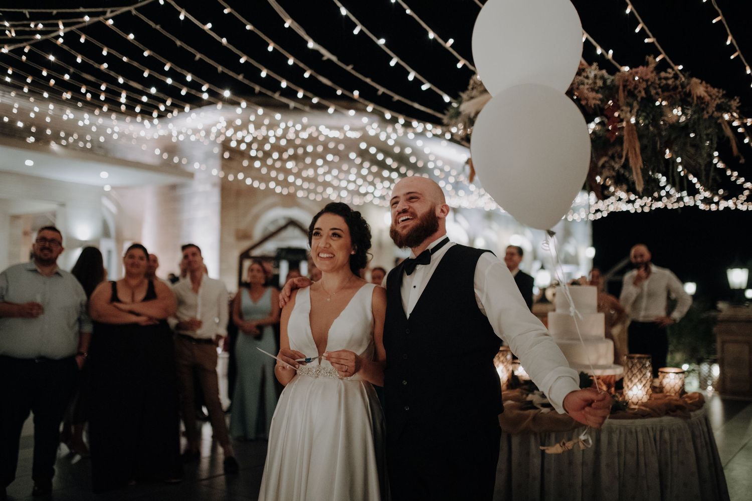 Wedding reception decorated with glowing string lights and white balloons creating magical atmosphere.