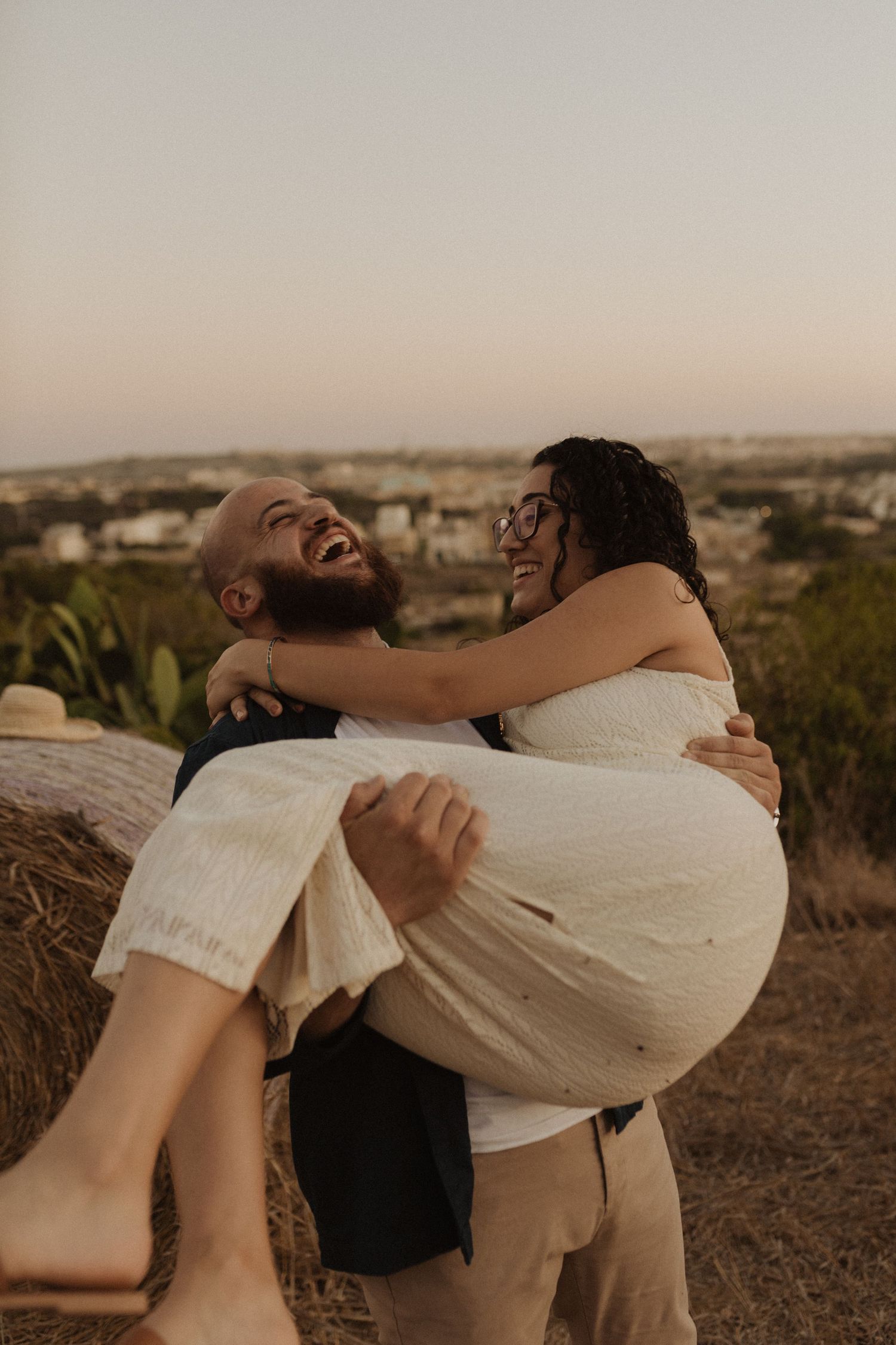 A joyful moment captured between a couple during sunset on a Mediterranean hillside.