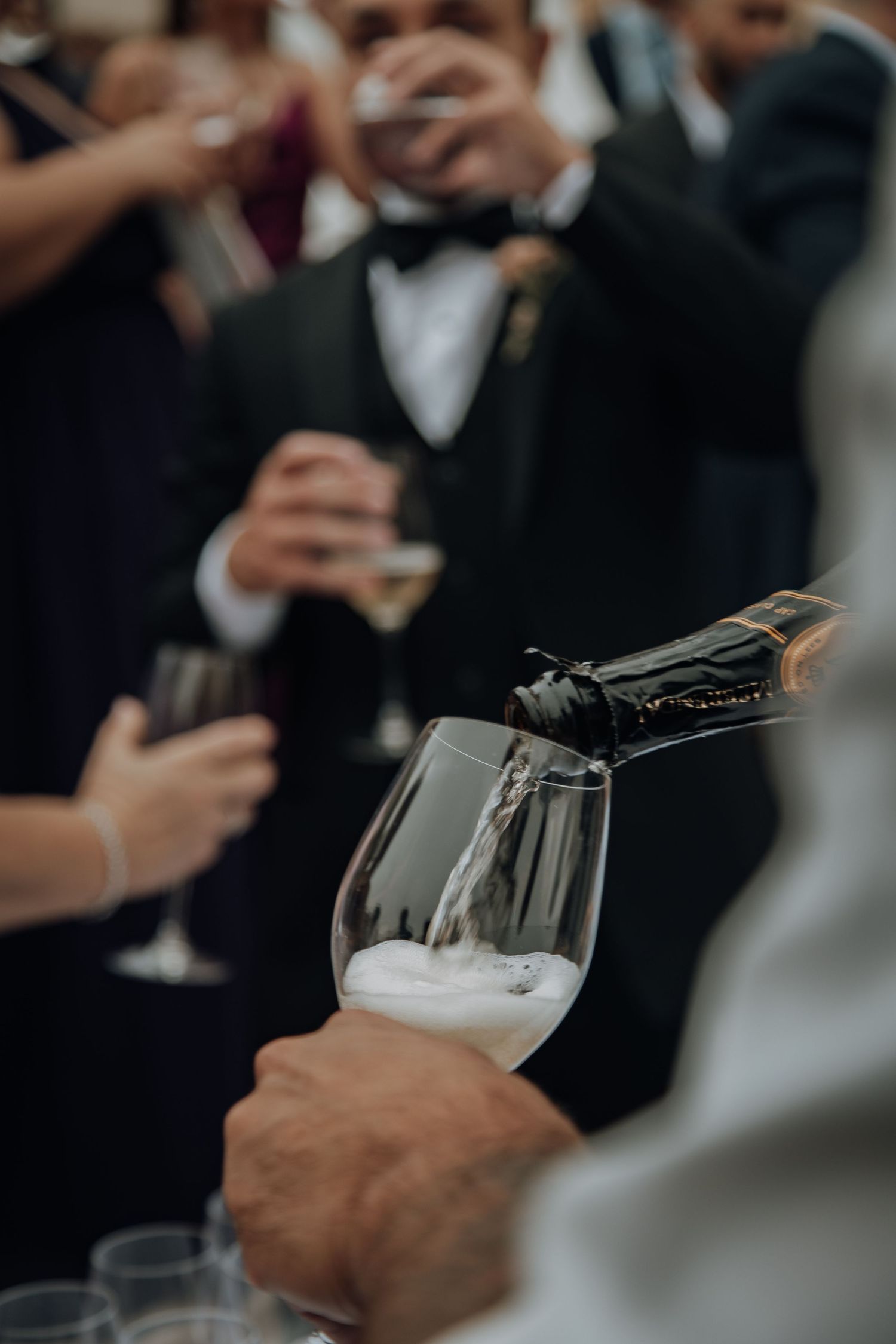 Champagne being poured into wine glasses during an elegant outdoor wedding reception.