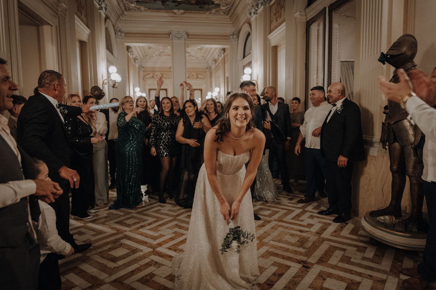 Wedding celebration in a grand hallway with geometric floor patterns and classic architecture.