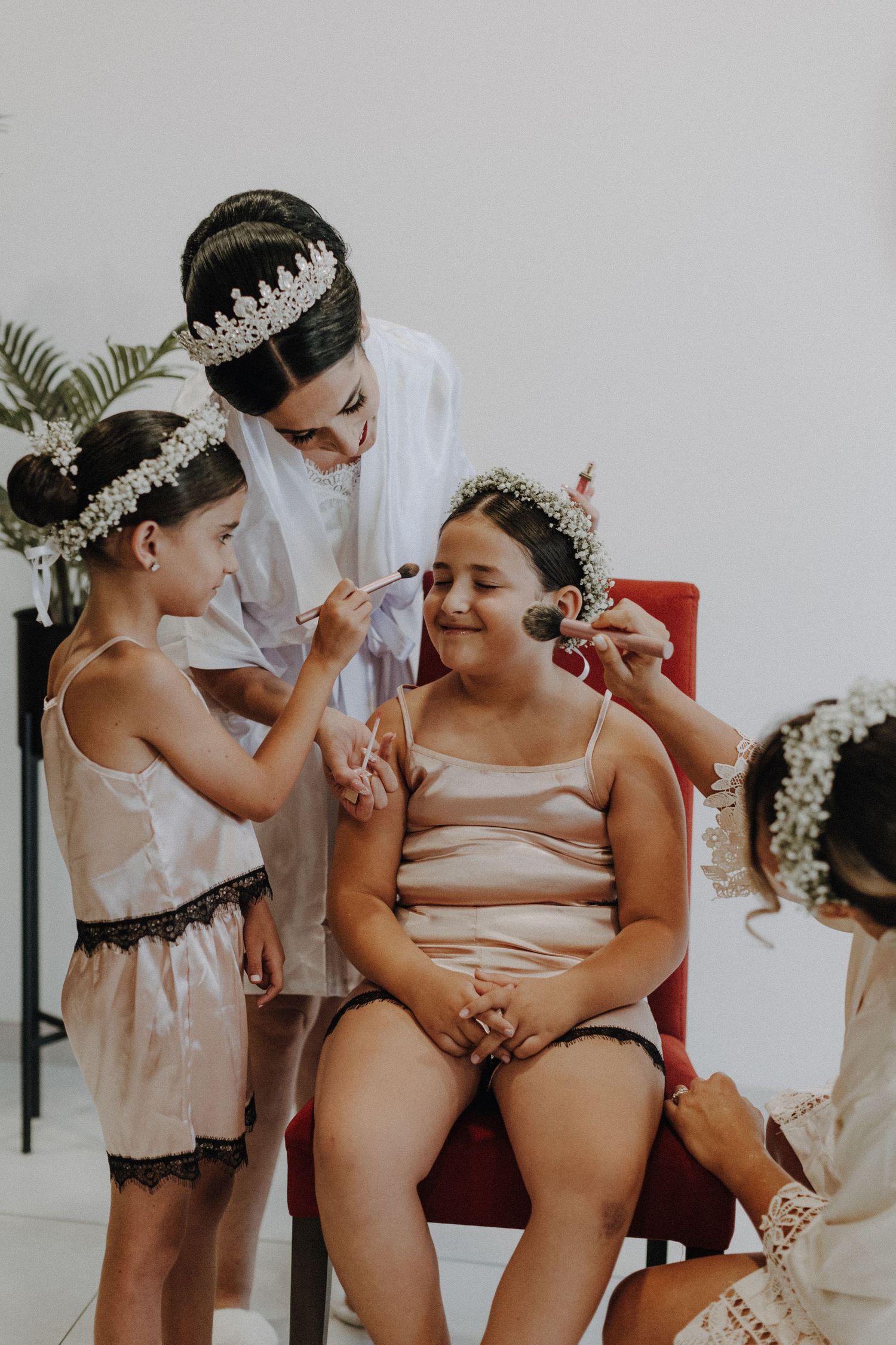 Children in floral crowns and white dresses gathered around getting ready for a special occasion.