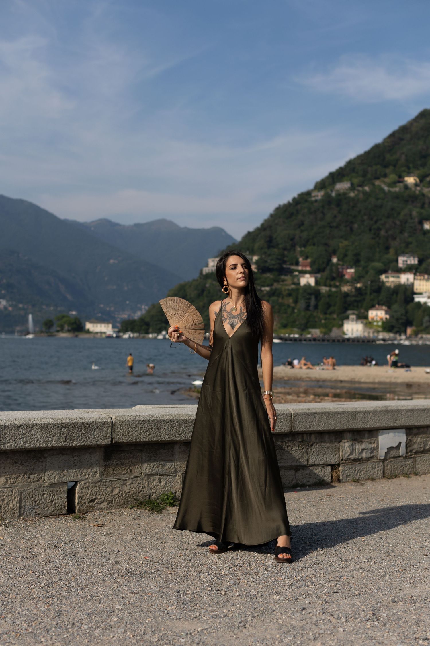 Fashion portrait by Lake Como featuring flowing dress against mountain landscape.