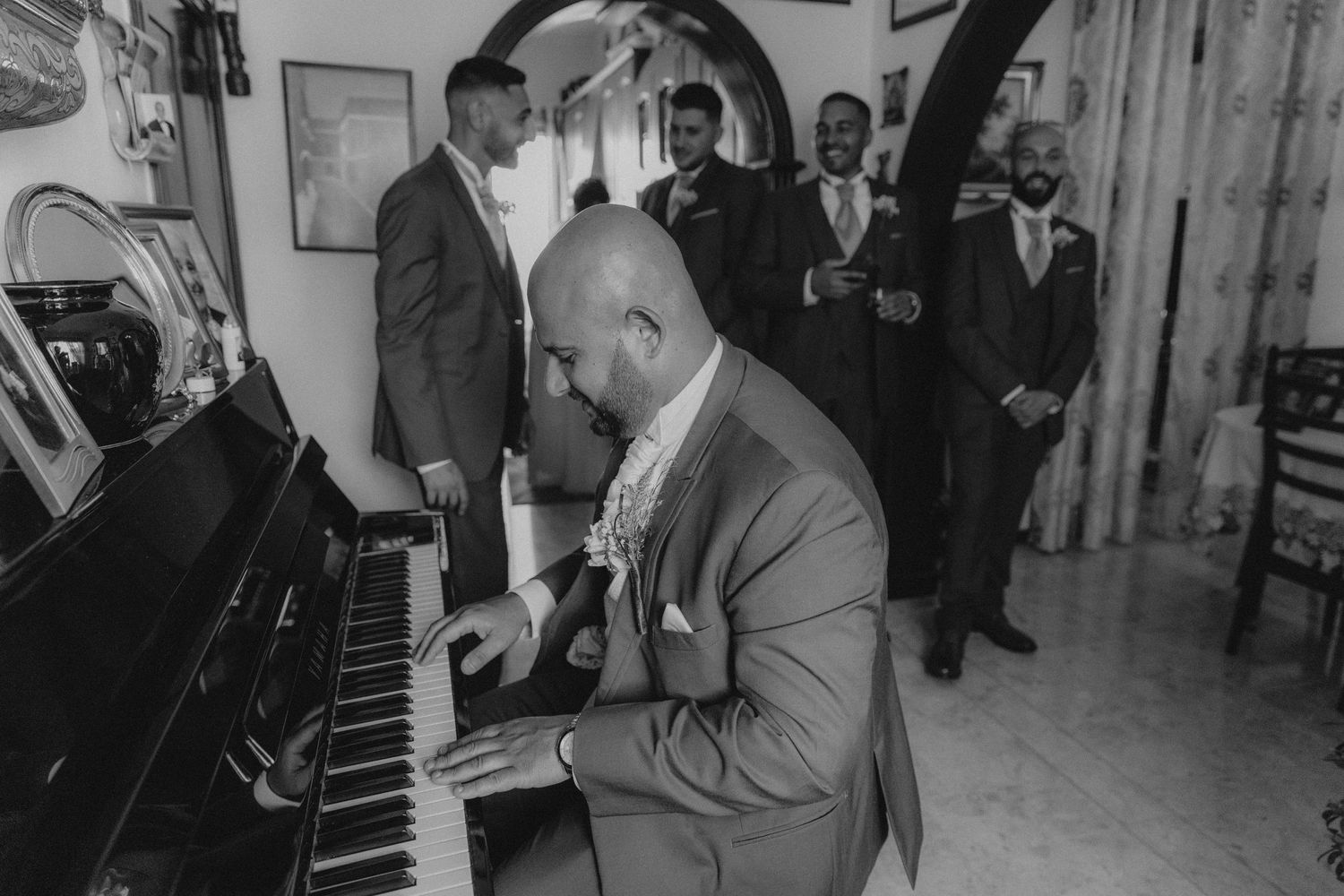 A guest playing piano at a formal event while others watch.