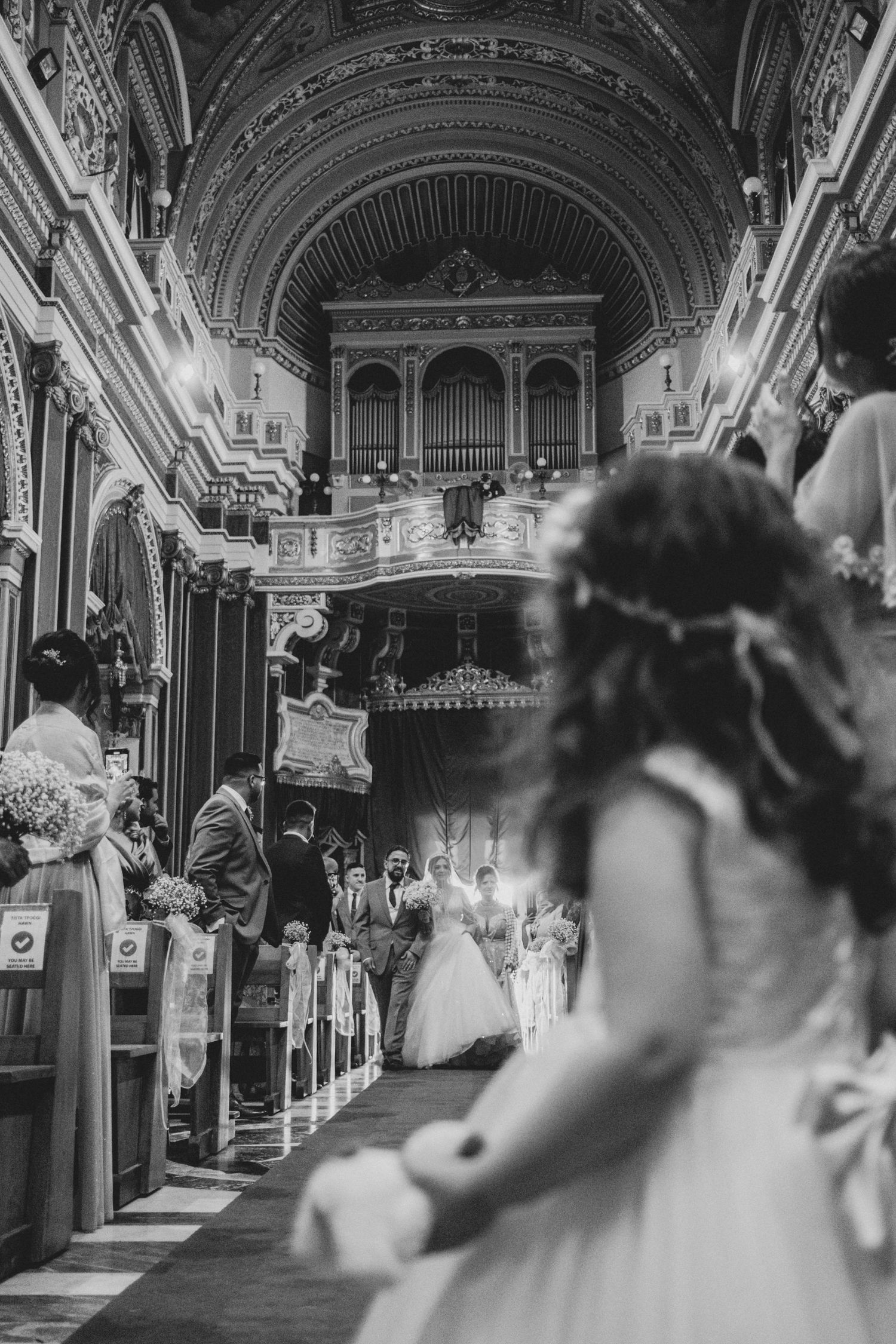 Black and white photo of a grand church interior with ornate architecture during a wedding ceremony.