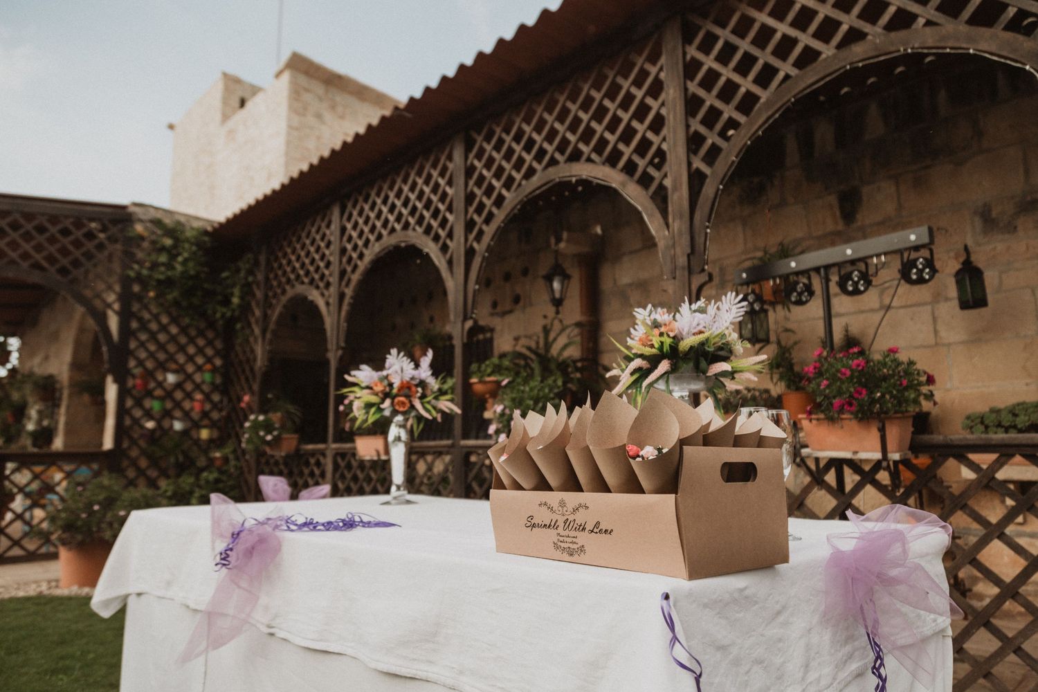 Wedding reception table setup under a rustic lattice archway with floral decorations.