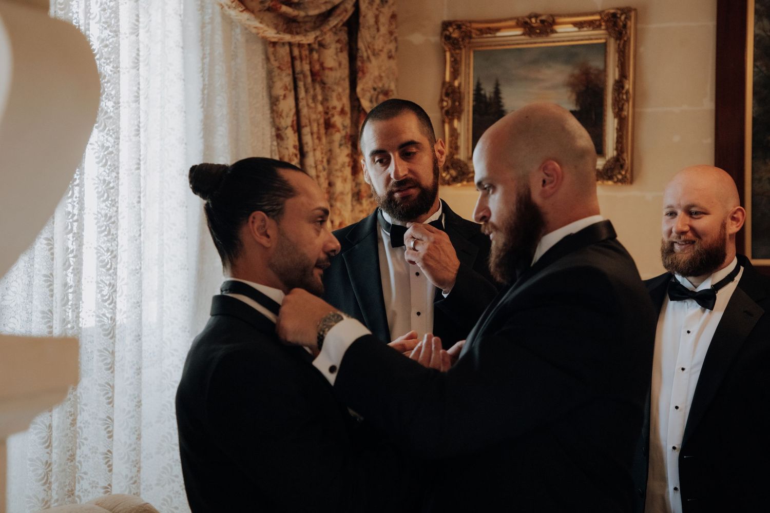 People in formal attire conversing in an elegantly decorated room with gold-framed artwork.