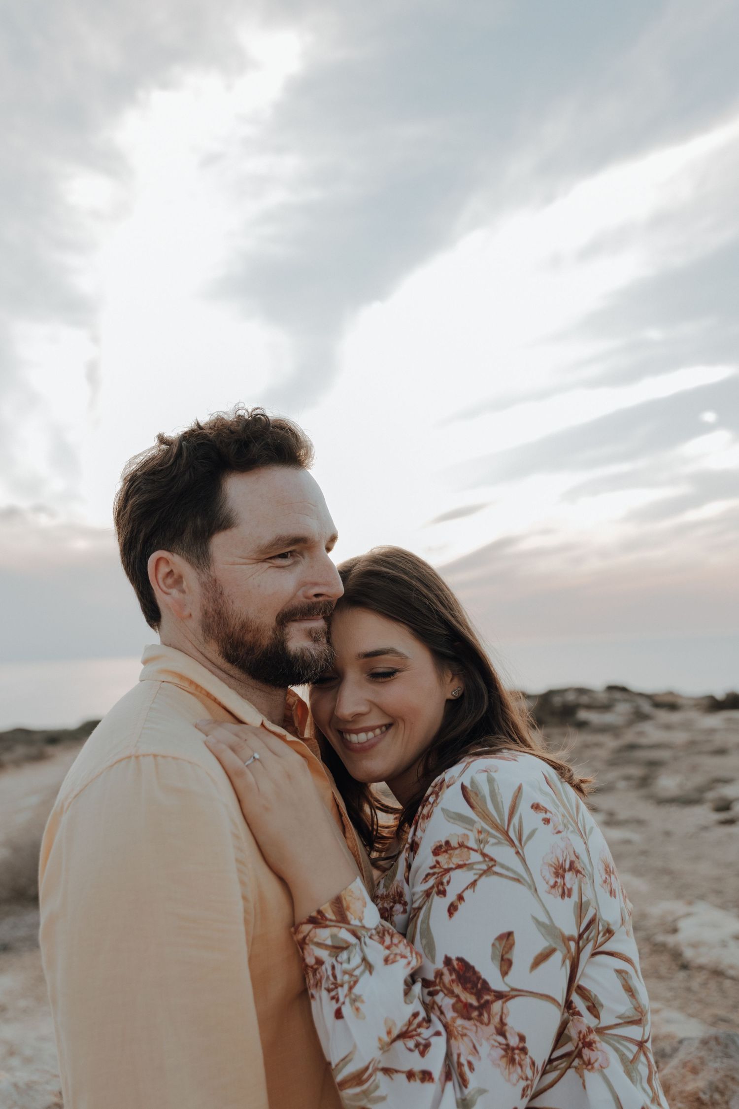 A romantic couple shares tender moments against a desert backdrop at sunset.