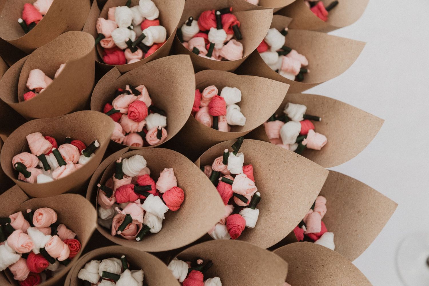 Brown paper cones filled with pink and white confetti petals arranged in a display.