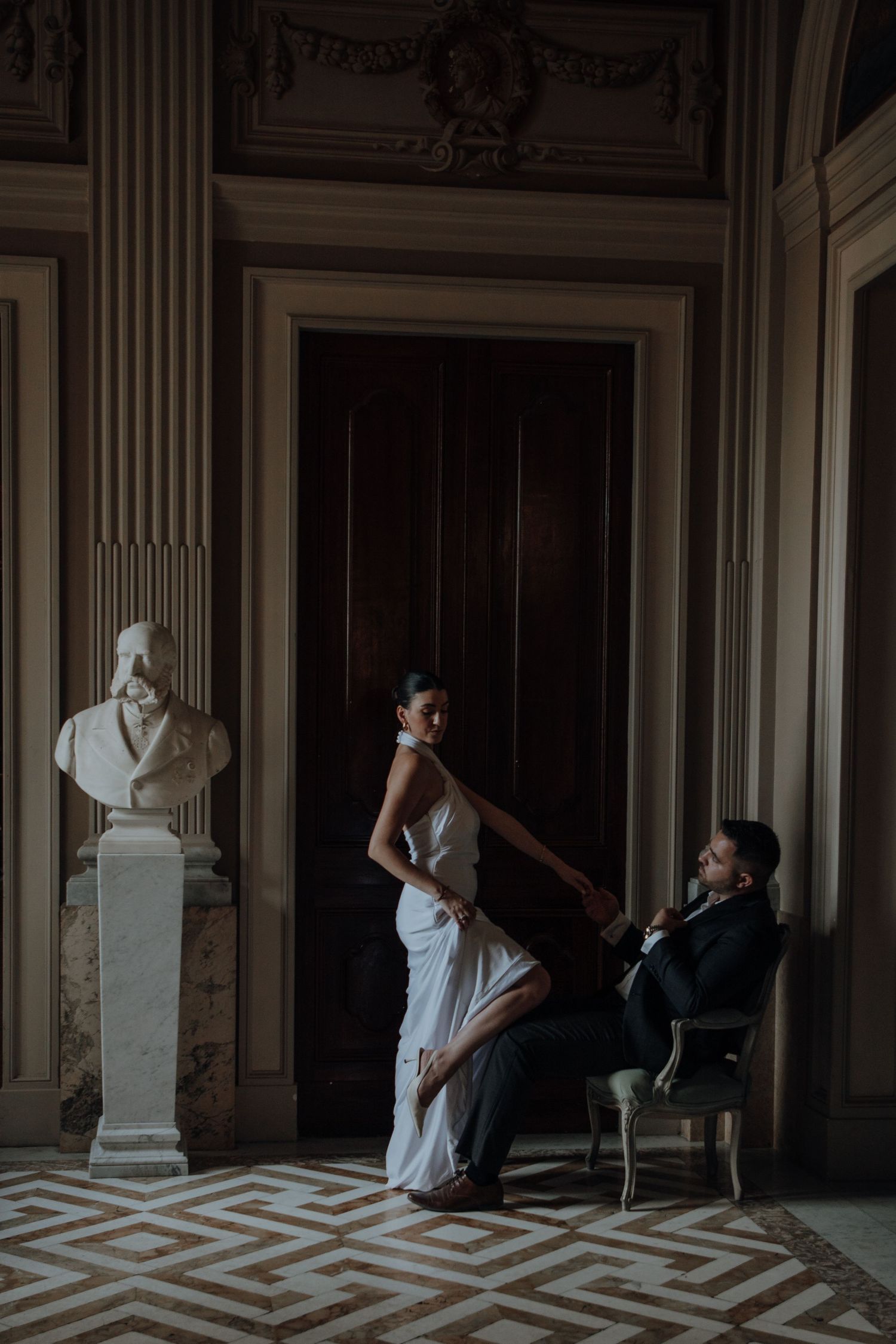 Artistic black and white photo in a grand room with geometric floor patterns and classical busts.