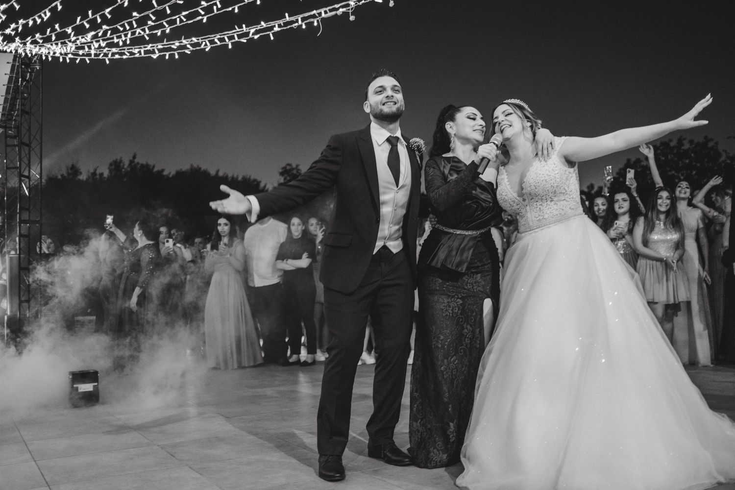 Wedding guests celebrating in formal attire under twinkling lights.