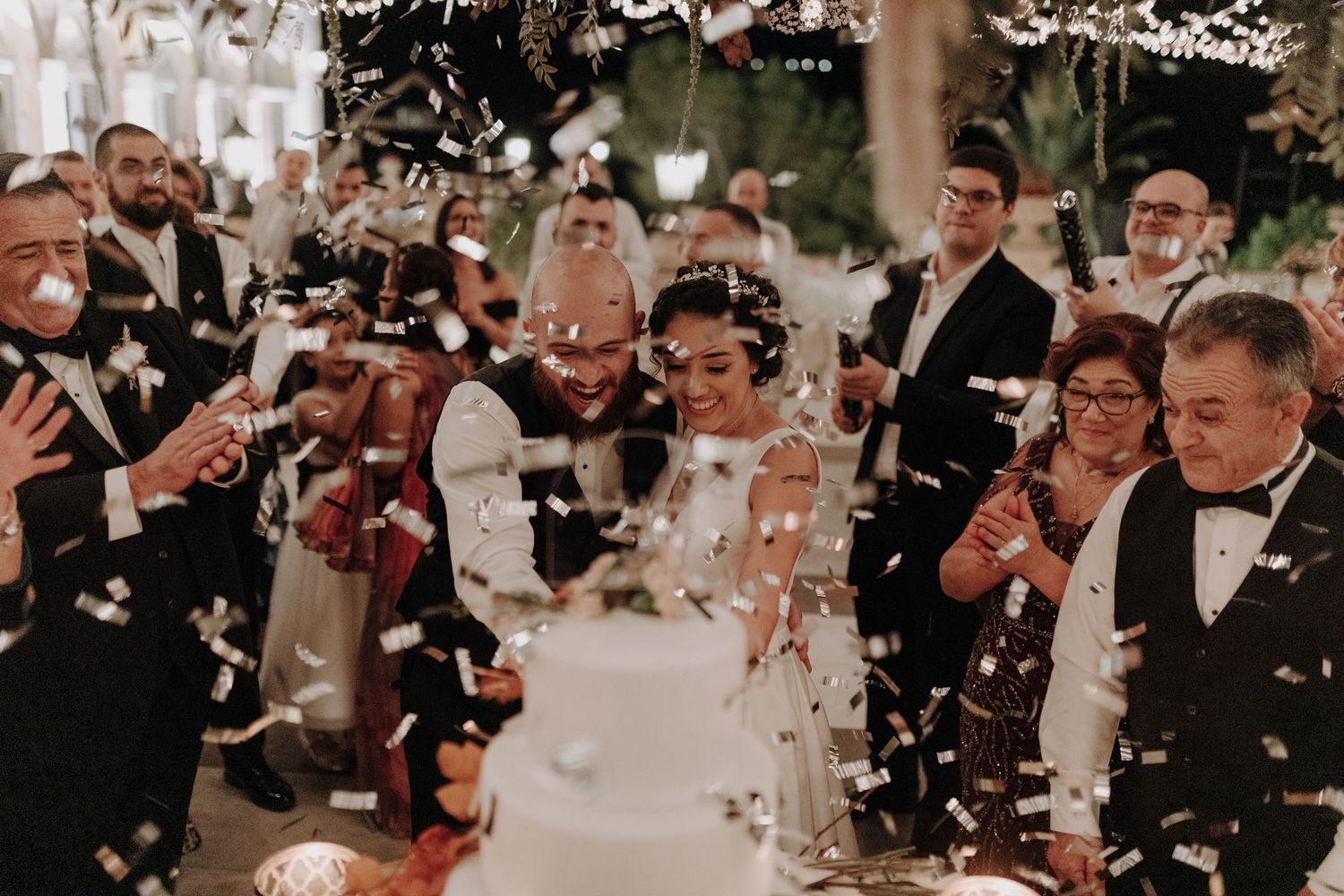 Joyful wedding celebration with confetti and sparklers lighting up the nighttime festivities.