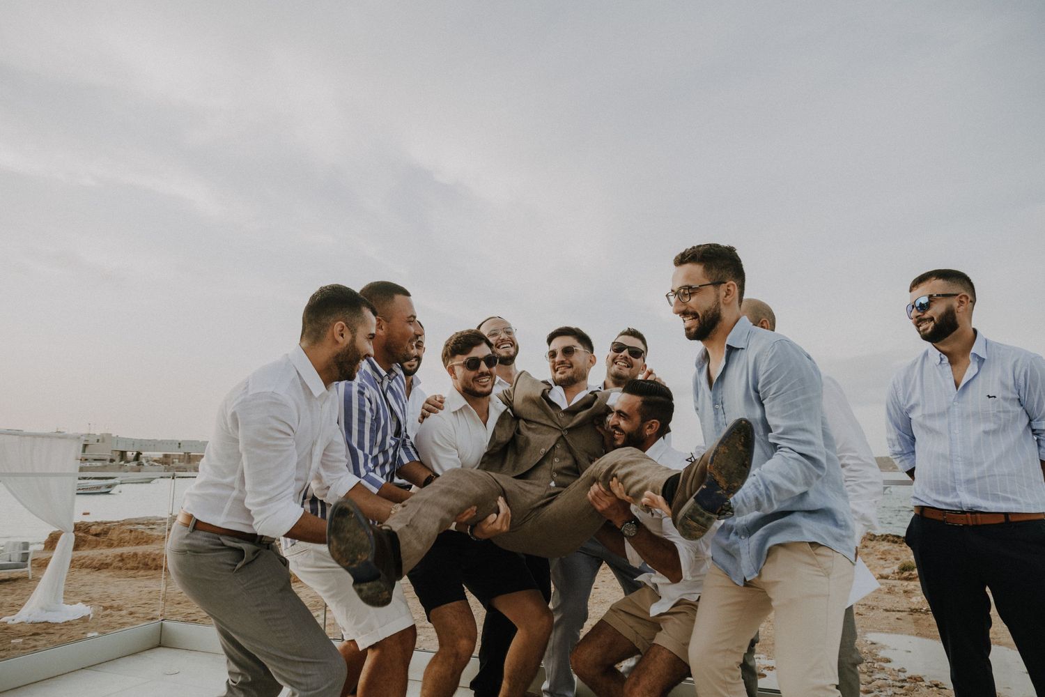 Candid shot of groomsmen celebrating outdoors with expressive movements and gestures.