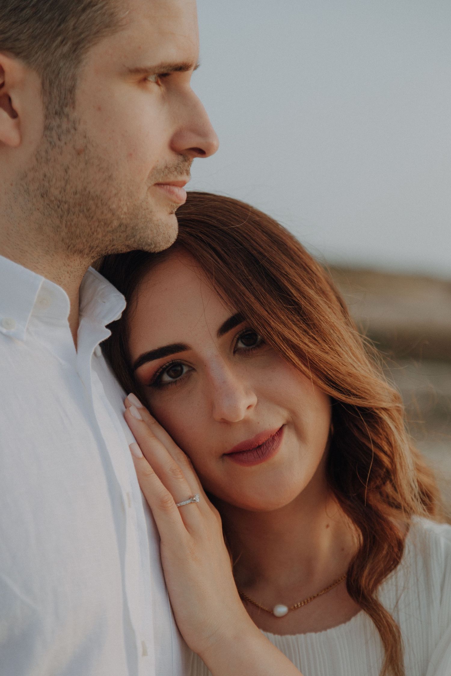 Intimate portrait of couple in white clothing against neutral background.