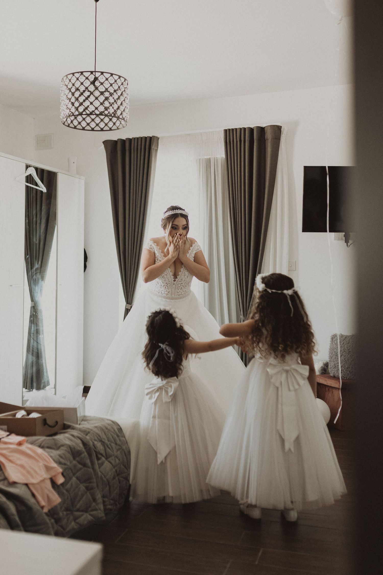 A dreamy wedding scene with a flowing white gown captured in an elegant indoor setting with floor-length curtains.