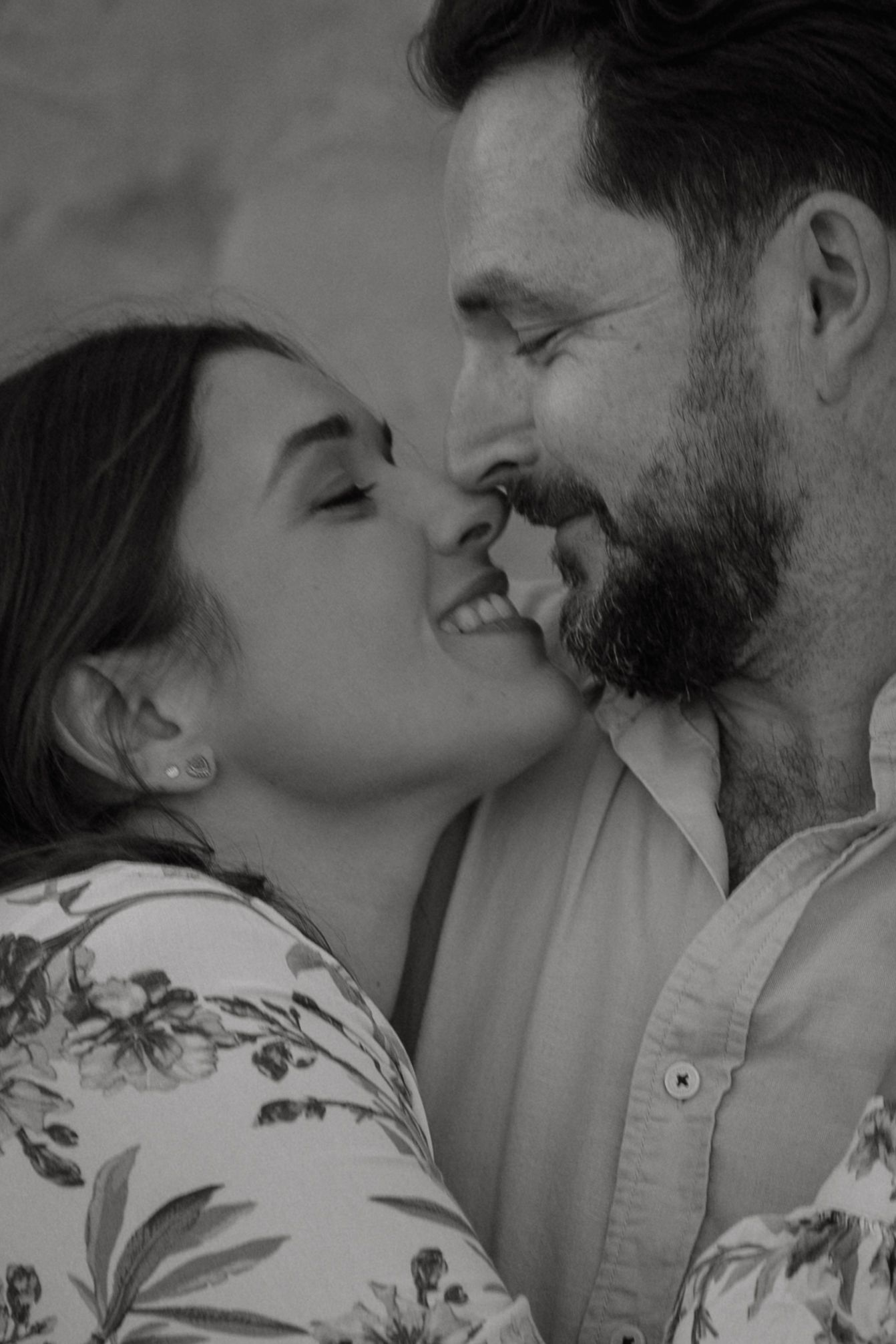 A romantic black and white close-up portrait of a couple sharing an intimate moment and smiling together.