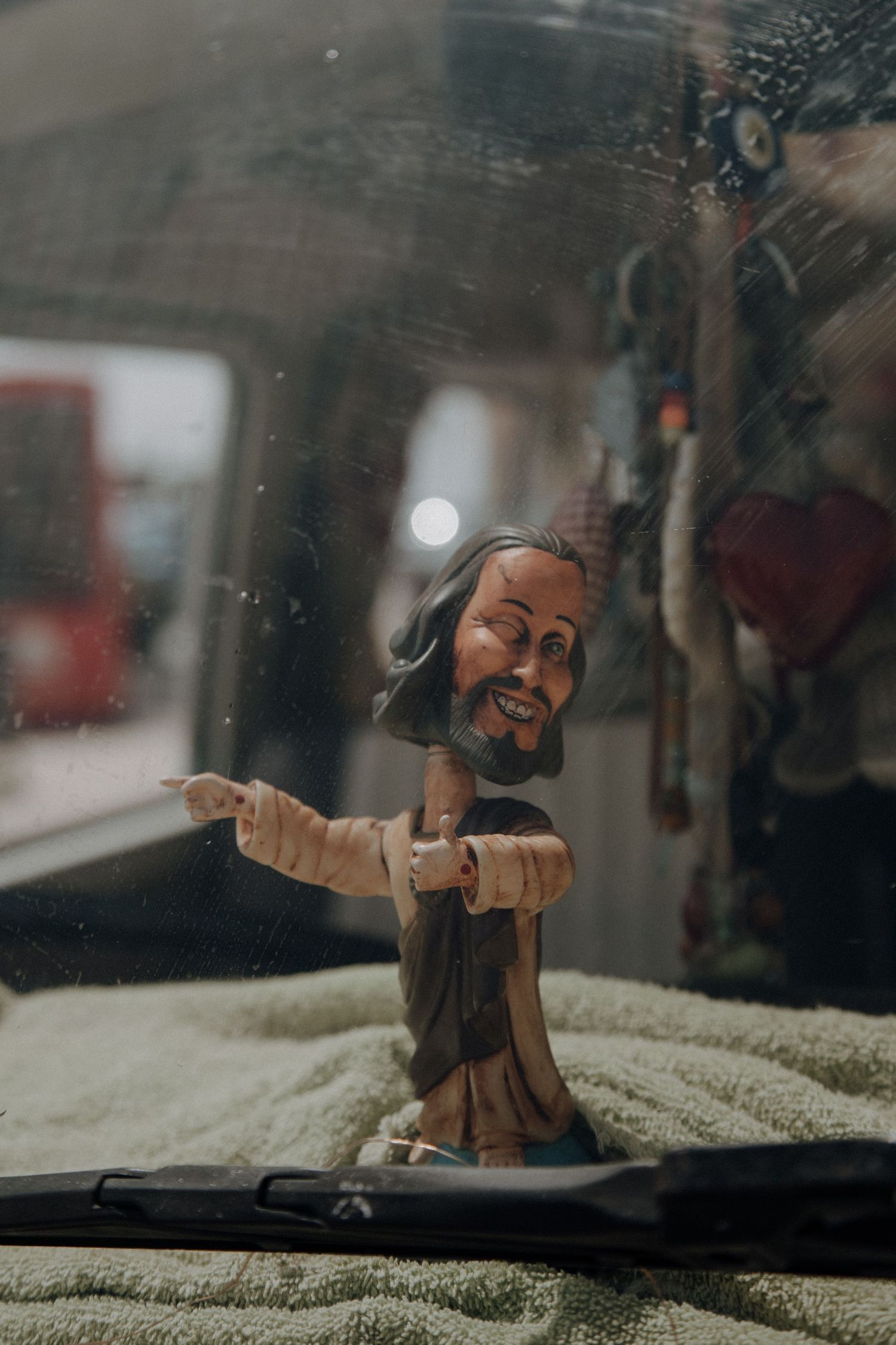 A wooden religious figurine on the dashboard of a vintage vehicle.