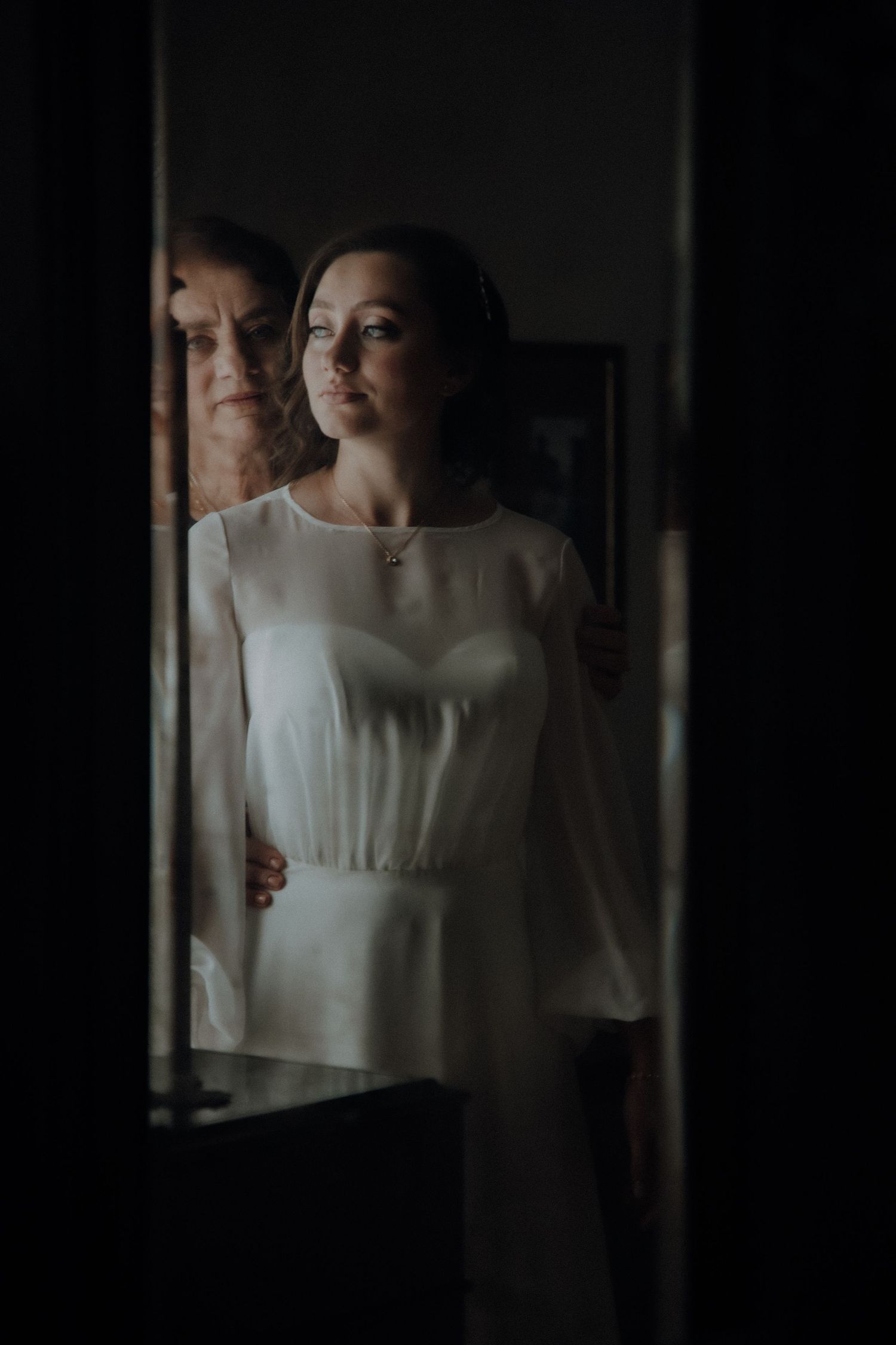 Dramatic lighting illuminates figure in white dress against dark background.