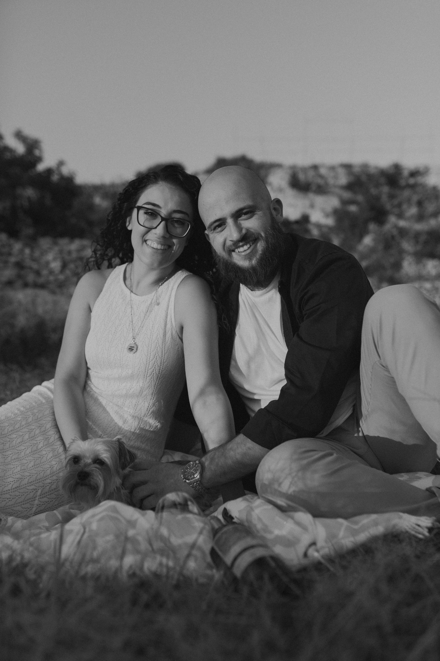 A couple lounging together on a blanket during an outdoor photoshoot.
