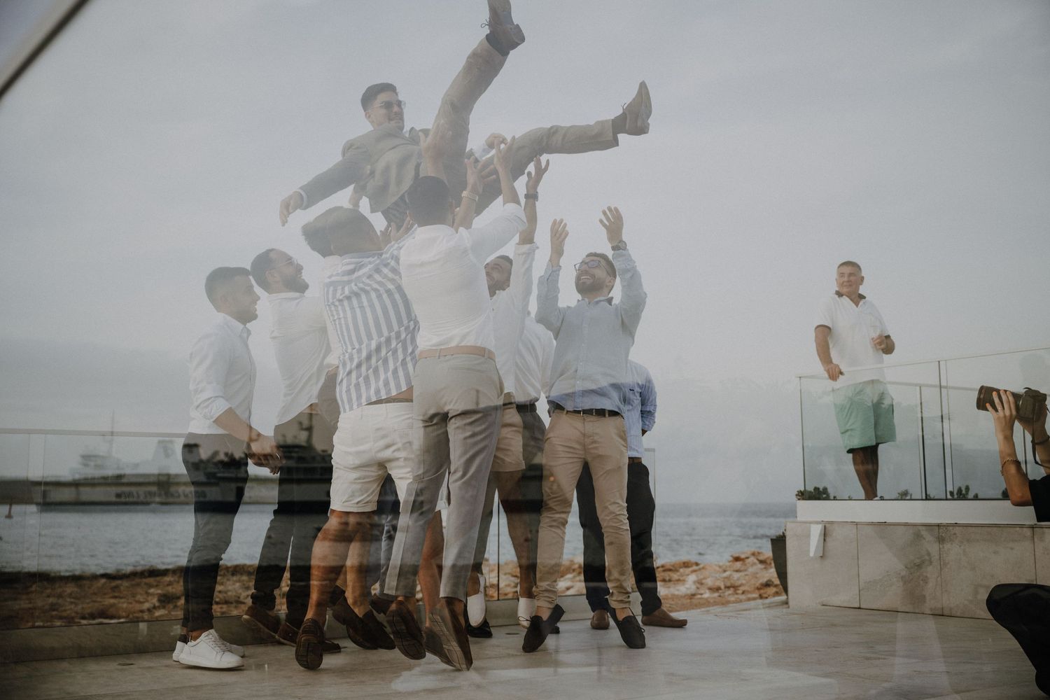 Wedding guests jumping and celebrating at outdoor seaside reception.