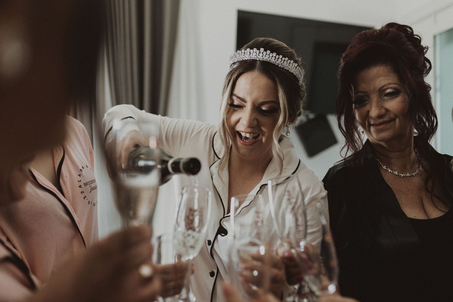 Wedding party pouring champagne and celebrating with candid expressions.
