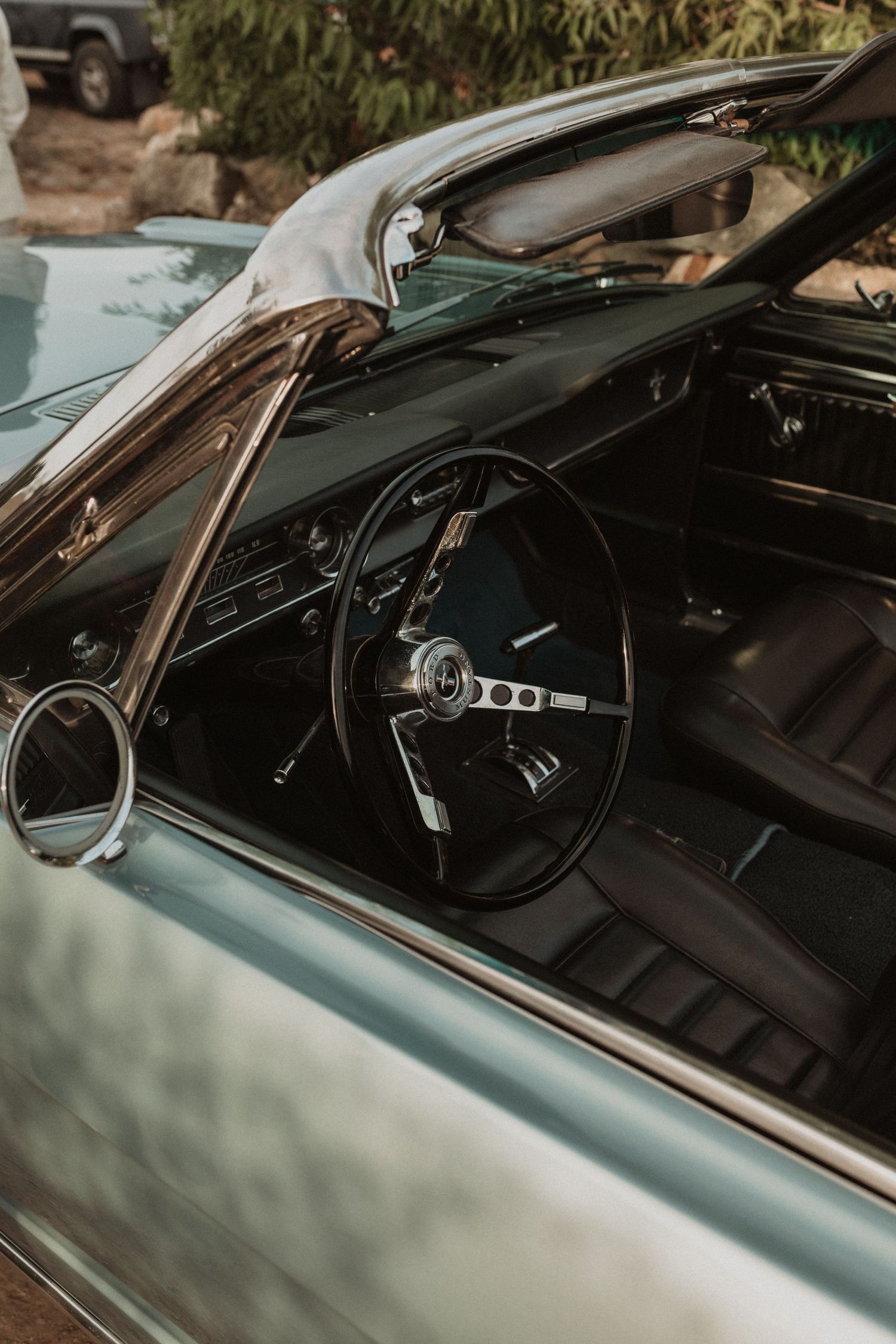 Interior dashboard and steering wheel view of a vintage car with black leather upholstery.