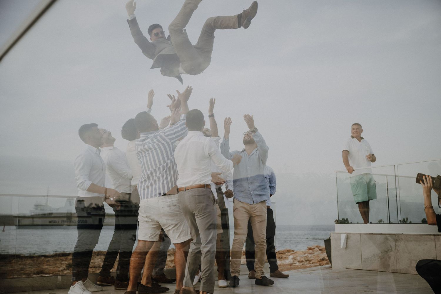 Group of celebrants leaping in joy at waterfront wedding celebration.