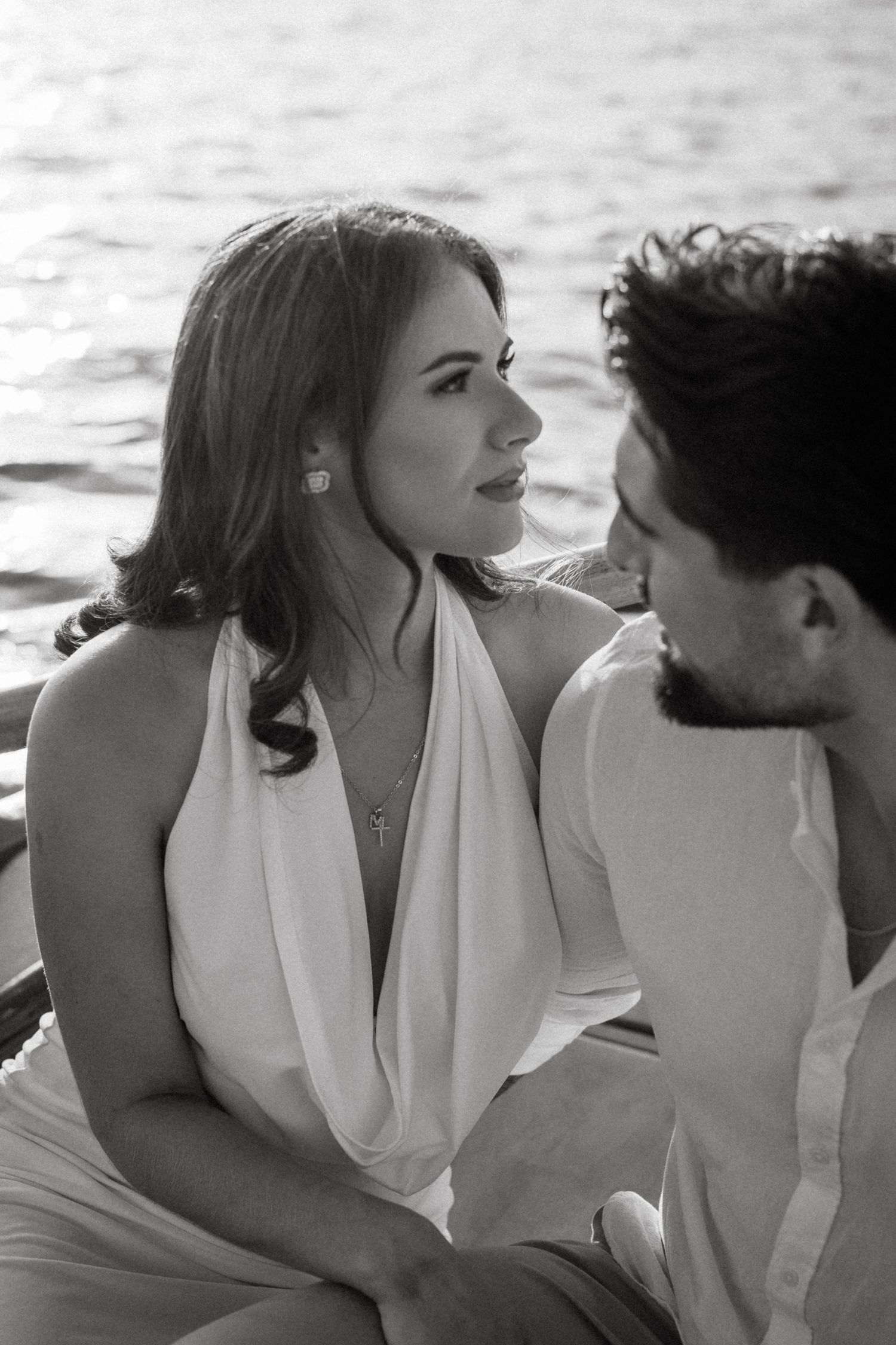 Intimate black and white portraits of a couple in white attire on a boat.