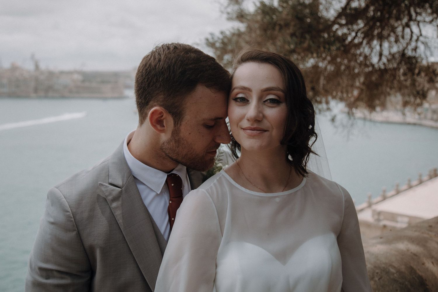 Wedding couple portrait series with coastal background in soft, muted tones.