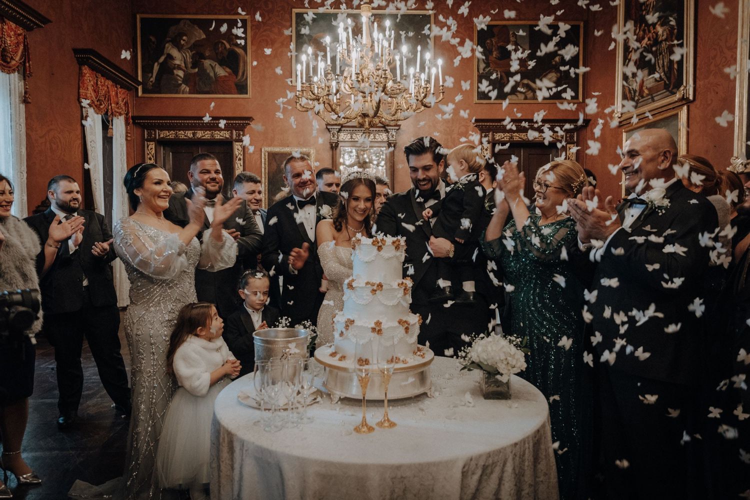 Wedding guests celebrate with confetti in an opulent ballroom setting.