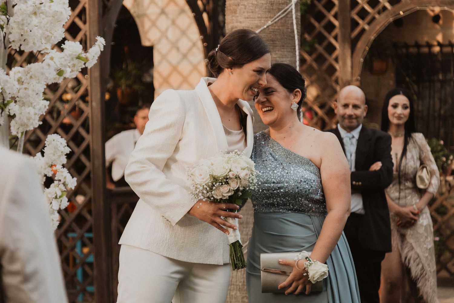 Wedding celebration with string lights and lattice backdrop as guests gather in semi-formal attire.