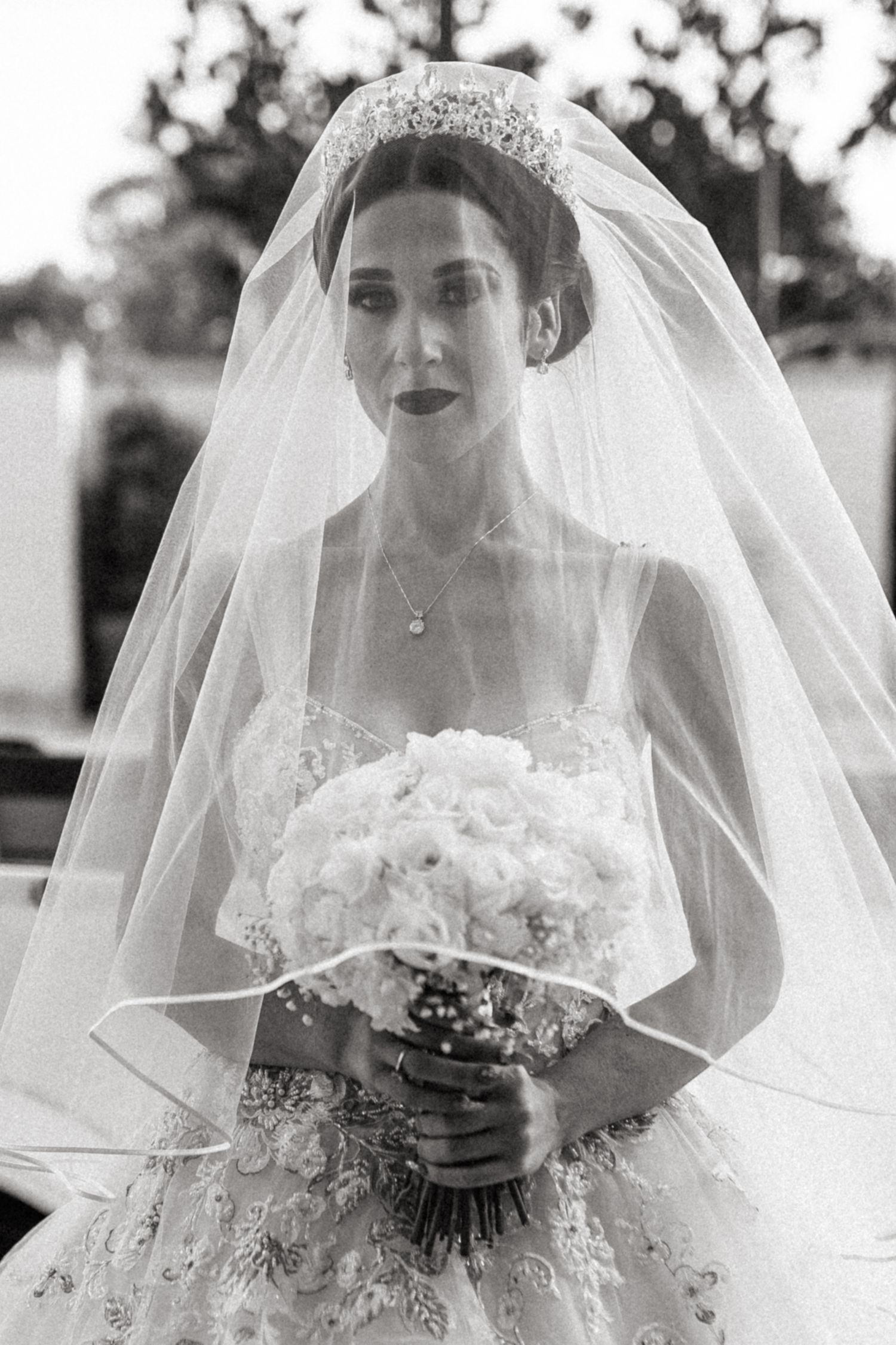 Classic black and white bridal portrait with veil and tiara holding white bouquet.