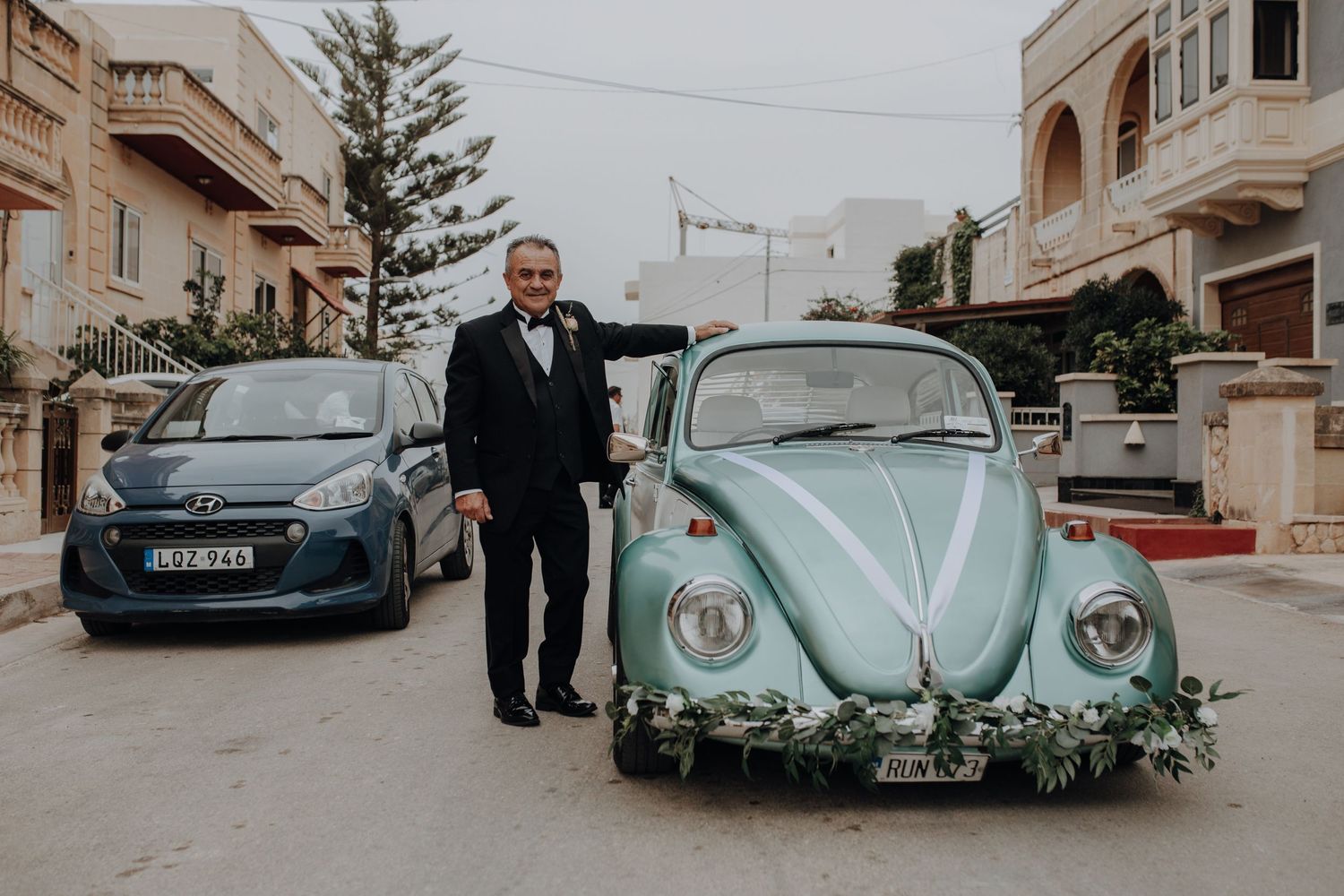 Classic vintage Volkswagen Beetles parked on a street outside Mediterranean-style buildings.