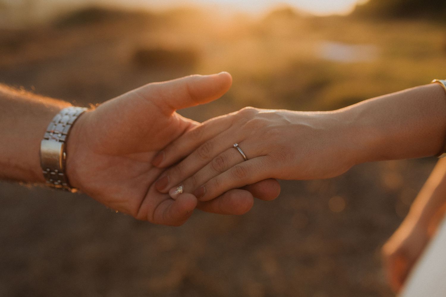 Hands reaching out to each other against a warm sunset backdrop.