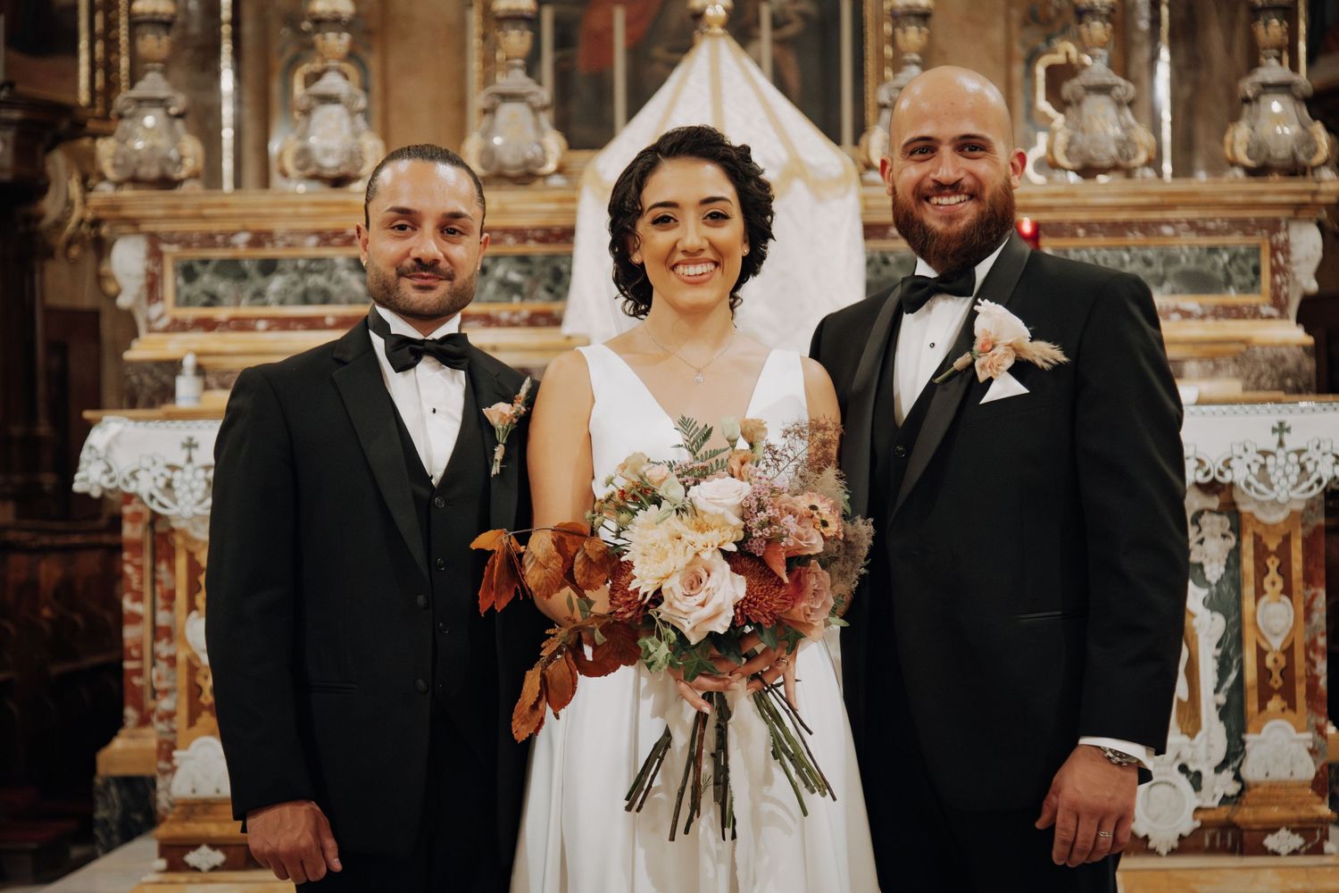 Wedding party poses at the altar in an ornate church sanctuary with vintage architectural details.