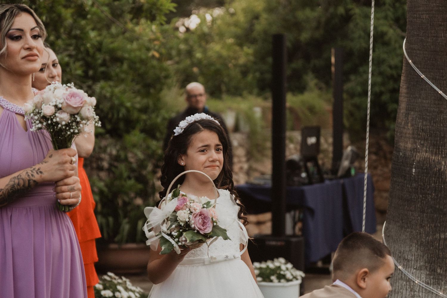 Outdoor garden wedding ceremony with guests in colorful attire and natural greenery.