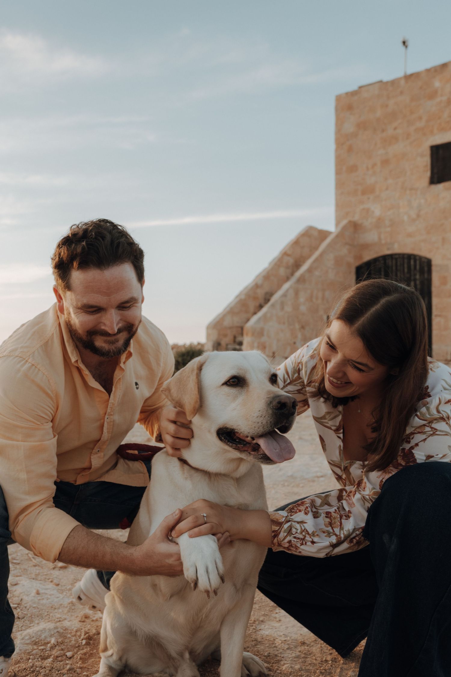 Yellow Labrador retriever enjoying playful moments with owners against a brick building backdrop.