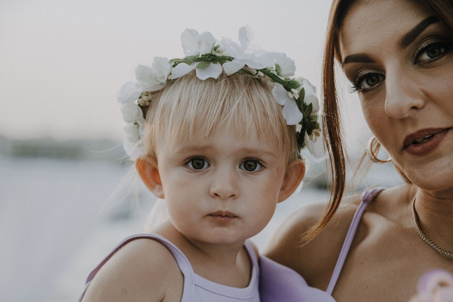 Close-up portrait of a small child wearing a floral headpiece.