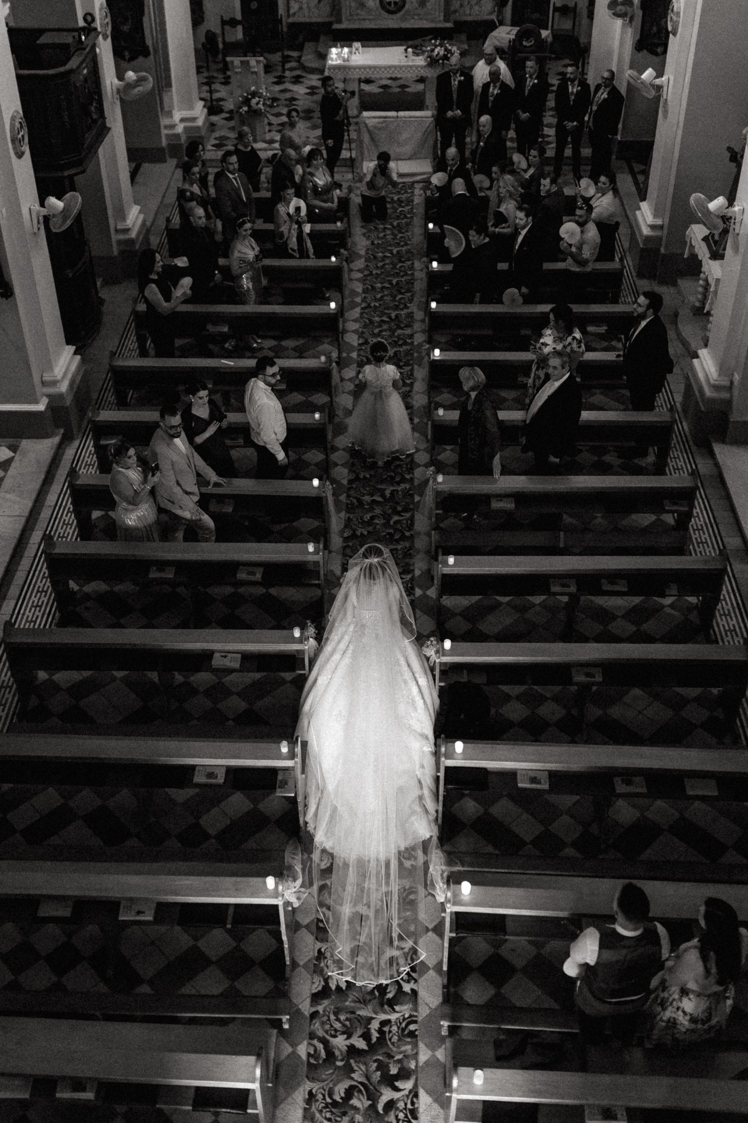 Black and white aerial view of a wedding ceremony inside a church showing bride and congregation from above.