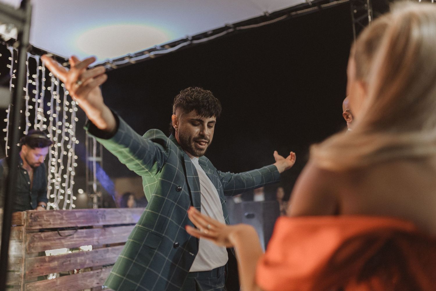 Guests dance enthusiastically under dim lighting at an indoor celebration.